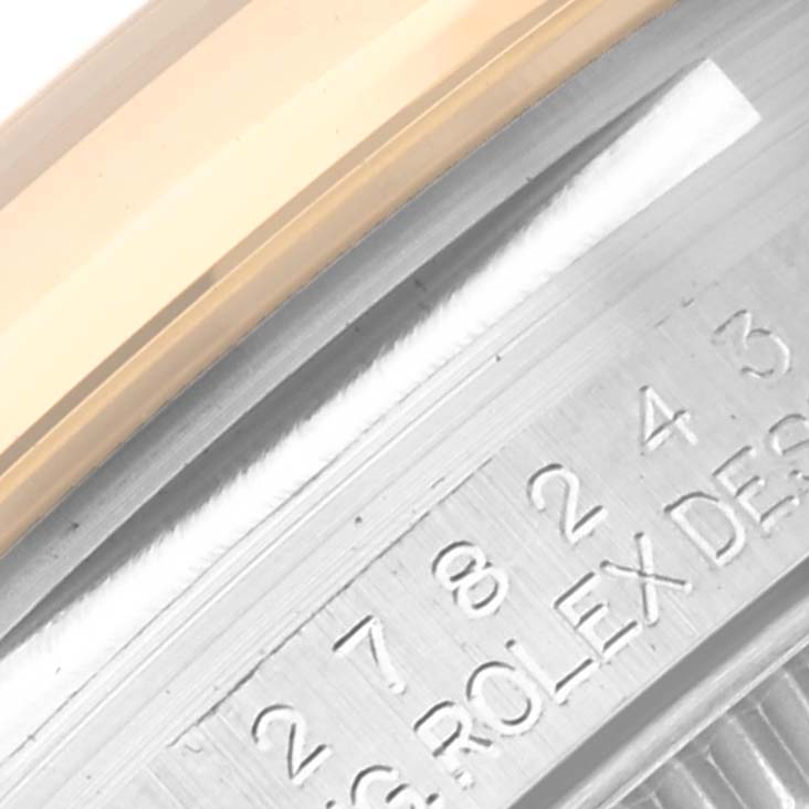 This image shows a close-up view of the bezel and fluted edge of a Mid-Size Rolex watch, along with part of the engraved serial number.