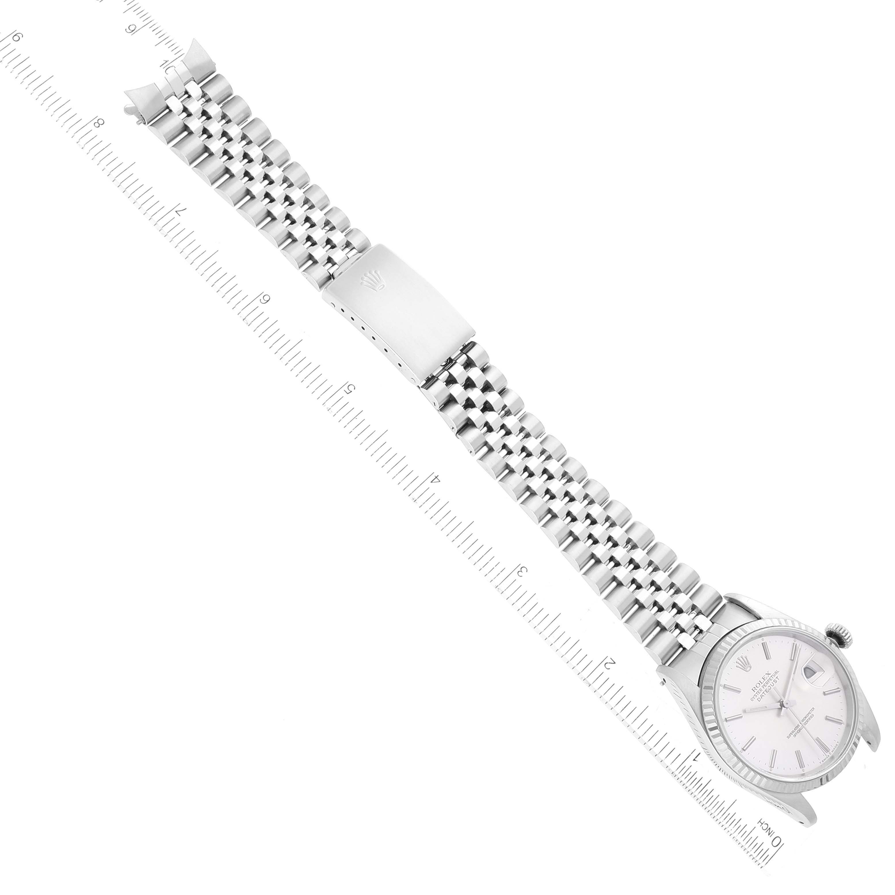 The image shows a top view of a Rolex Datejust 16234 Men's Stainless Steel Silver Dial 16234 Men's Stainless Steel Silver Dial watch with its face, bracelet, and clasp aligned along a measuring ruler.