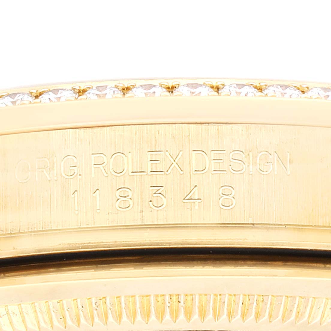 The image shows a close-up of the Rolex President 118348 Men
s Yellow Gold Champagne Dial 118348 Men
s Yellow Gold Champagne Dial model
s side with the engraved bezel and part of the diamond-set bezel.