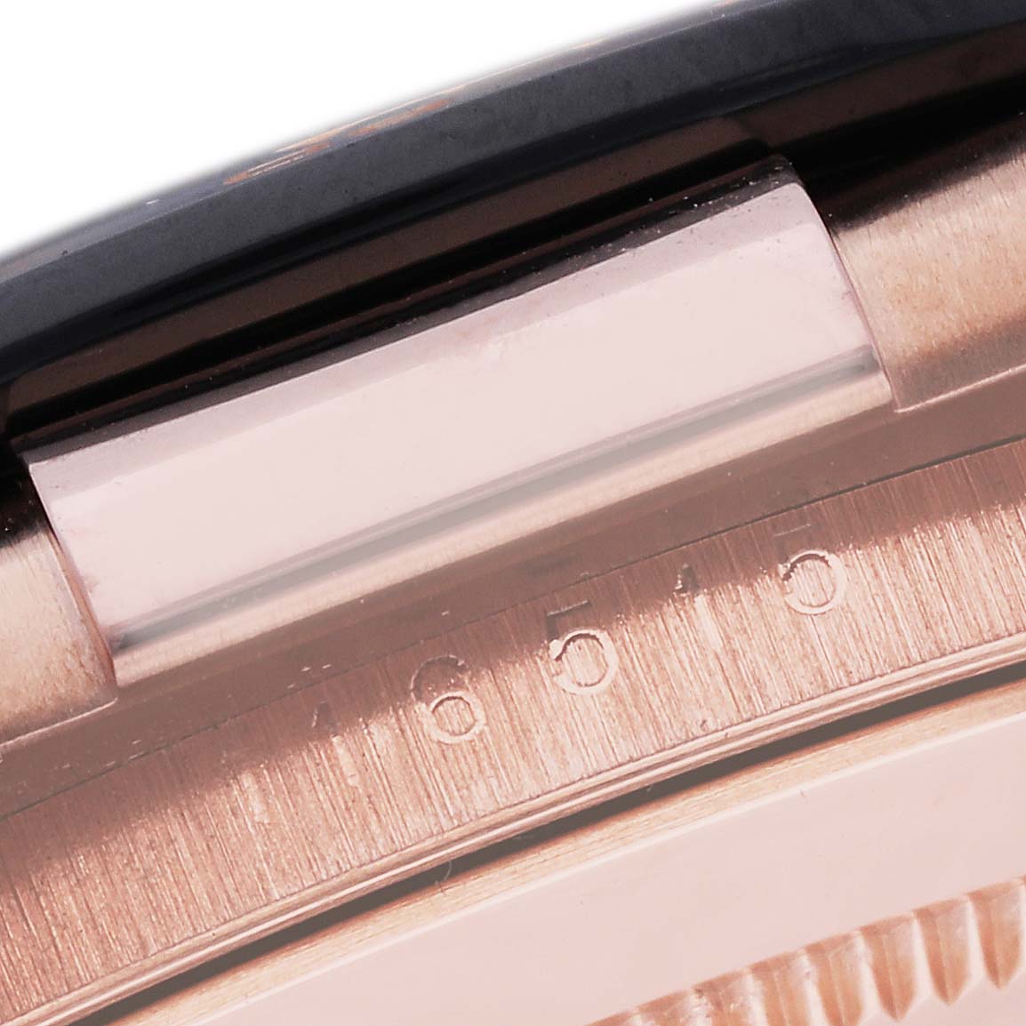 This close-up shows the case's edge, serial number, and part of the bezel of a Rolex Daytona 116515 Men's Rose Gold Black Dial 116515 Men's Rose Gold Black Dial model.