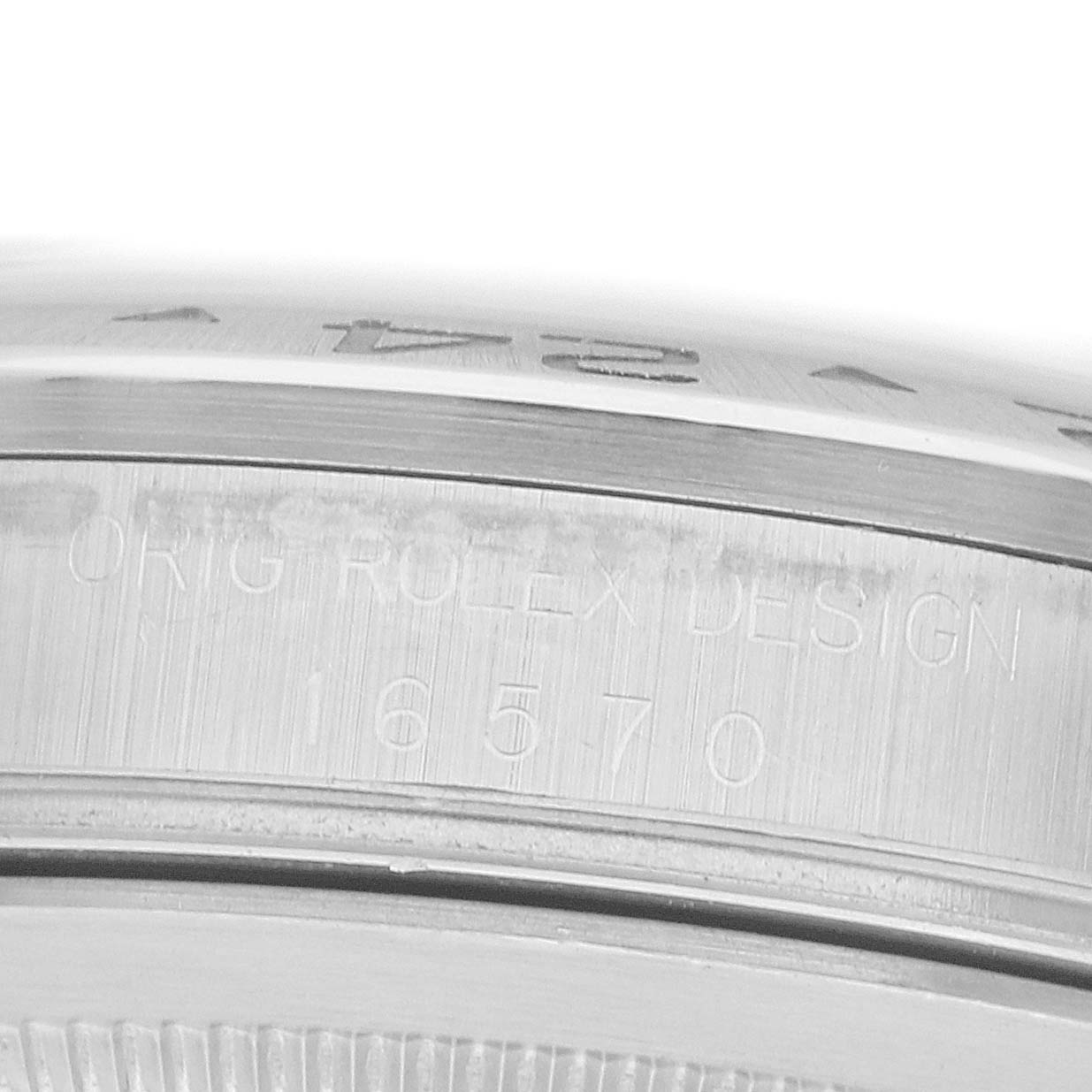 The image shows a close-up of the side of a Rolex Explorer 16570 Men
s Stainless Steel Black Dial bezel with engraved text, including the model number.