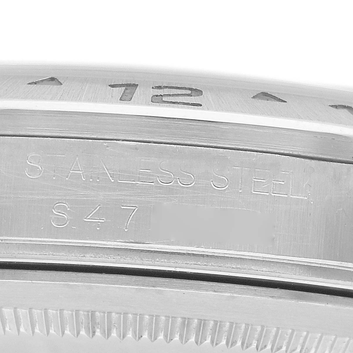 The image shows a close-up side view of a Rolex Explorer 16570 Men
s Stainless Steel Black Dial watch bezel with engraved markings and text indicating "STAINLESS STEEL".