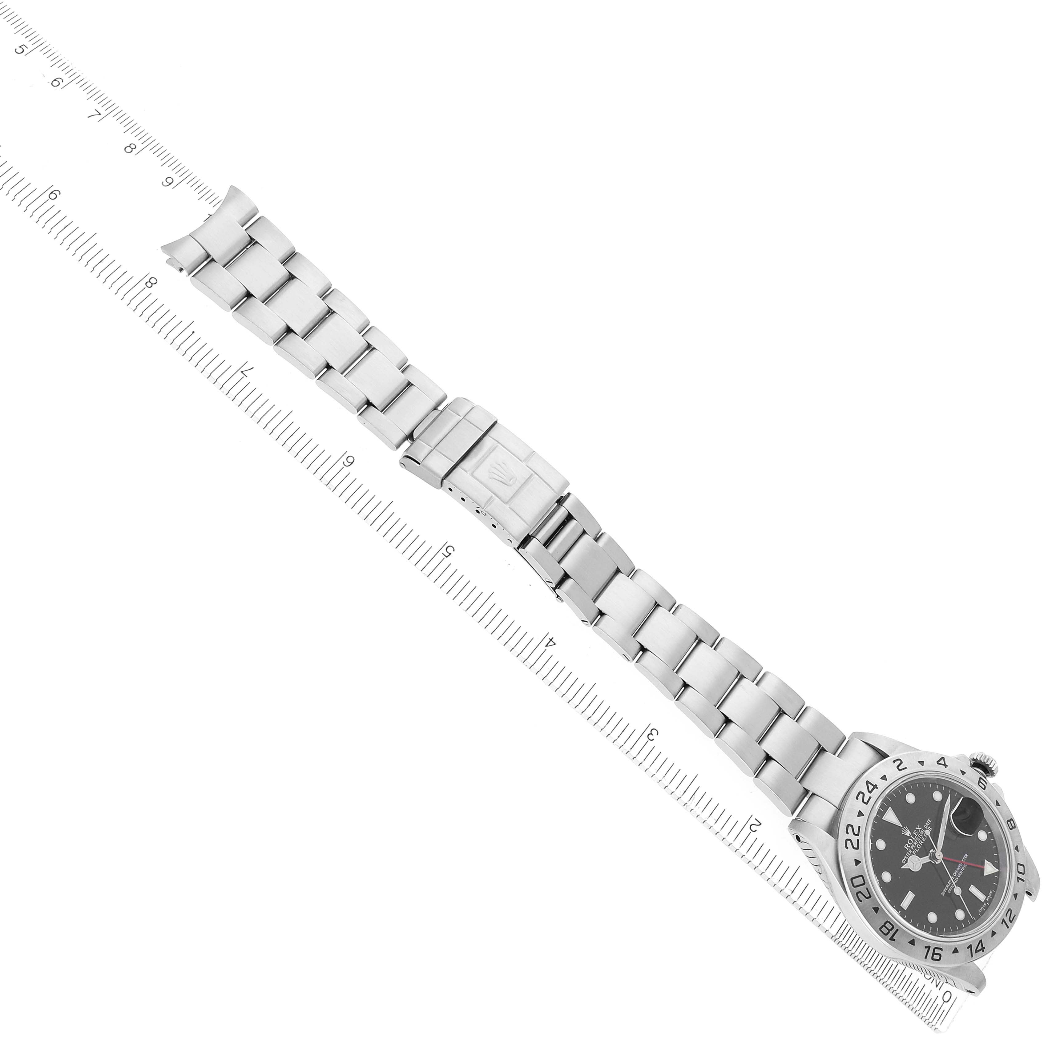 The Rolex Explorer 16570 Men
s Stainless Steel Black Dial watch is shown at an angle displaying its bracelet, clasp, and face, with a ruler measuring its length.
