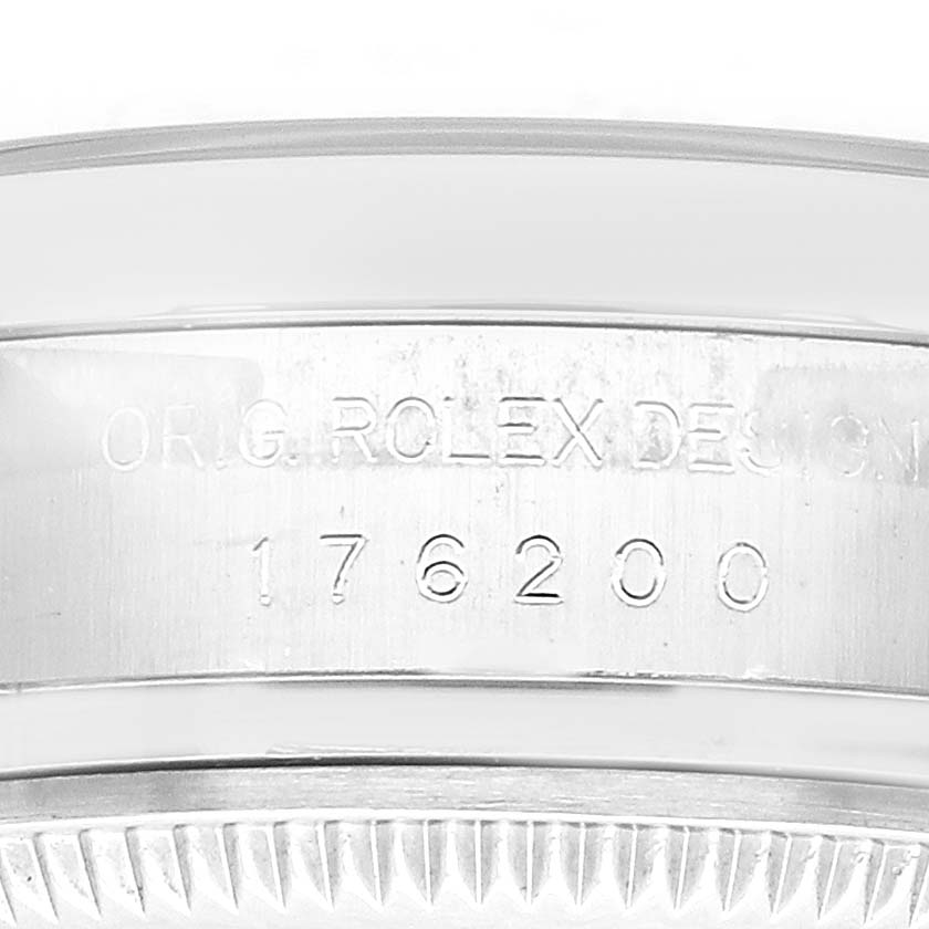 The image shows a close-up of the engraved bezel from a Rolex Oyster Perpetual 176200 Women
s Stainless Steel Black Dial watch, focusing on the serial number.