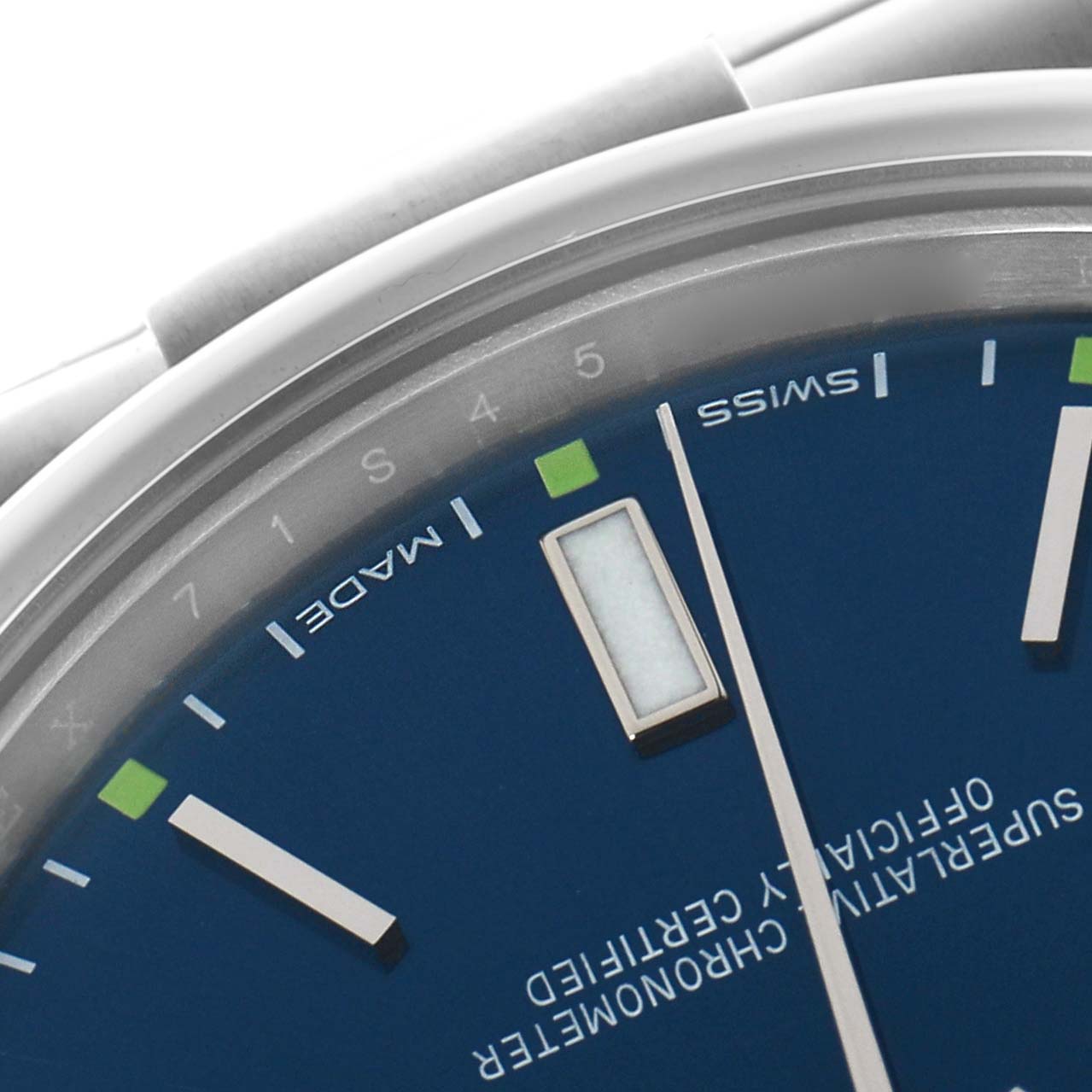 The image shows a close-up of the Rolex Oyster Perpetual 114300 Men
s Stainless Steel Blue Dial watch face, focusing on the dial
s edge and markers.