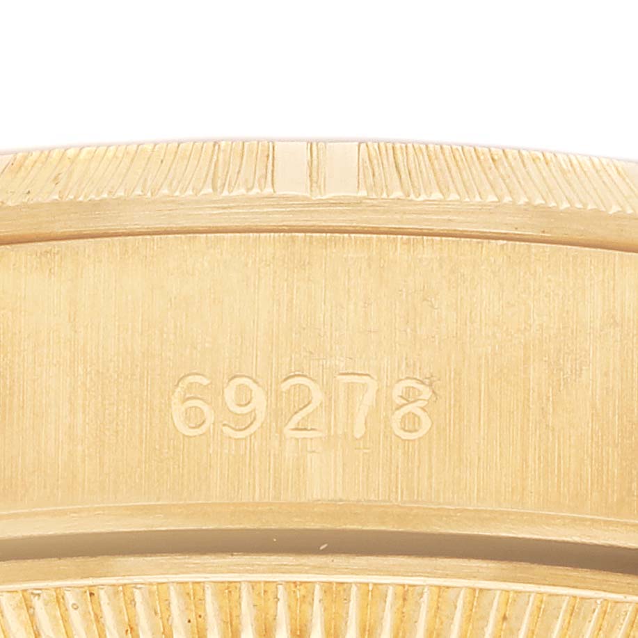 The image shows a close-up of the edge of the Rolex President 69278 Women
s Yellow Gold Champagne Dial model
s gold watch case, featuring the number "69278."