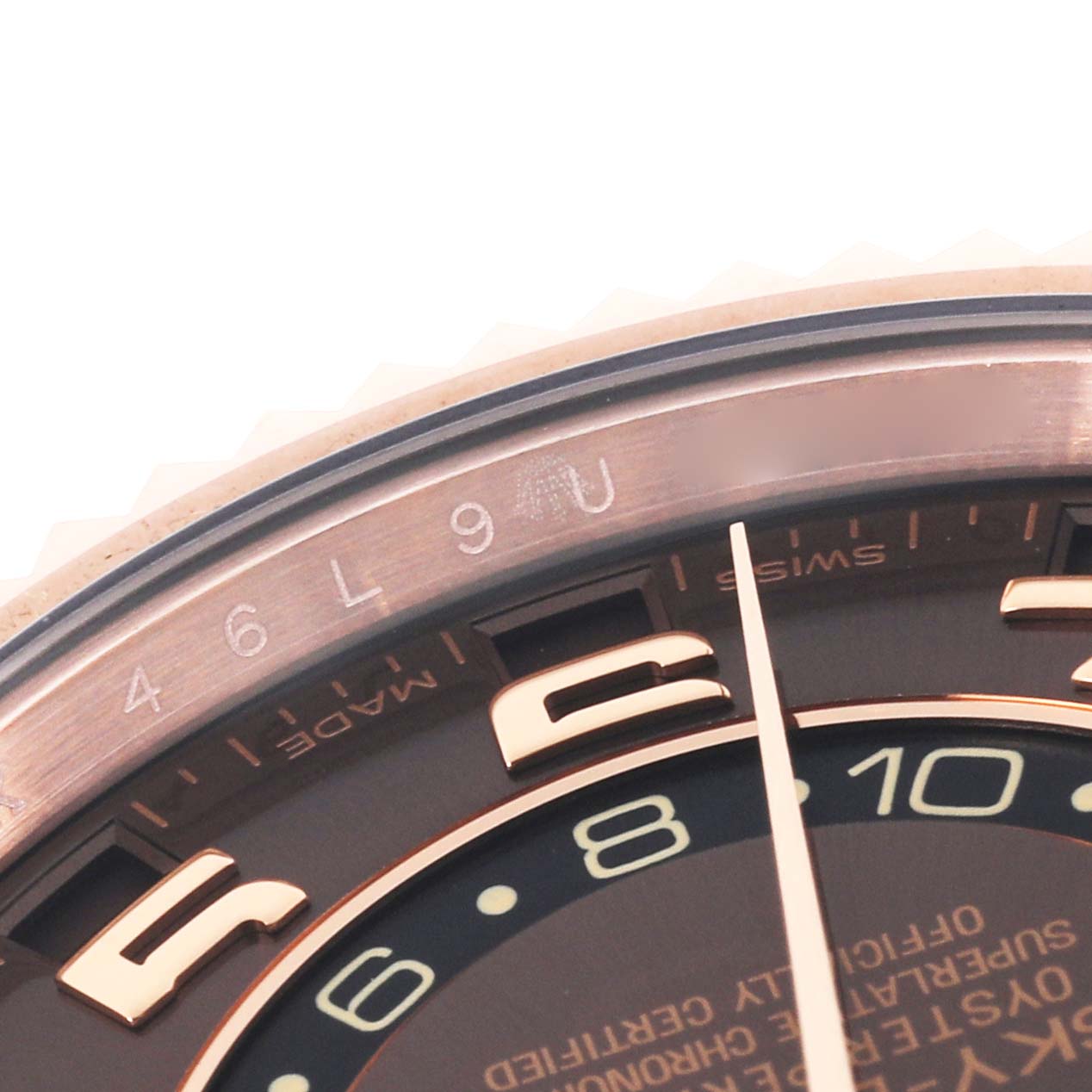 This close-up image of a Rolex Sky-Dweller 326135 Men
s Rose Gold Brown Dial 326135 Men
s Rose Gold Brown Dial watch displays the edge of the dial, some hour markers, and a portion of the bezel.