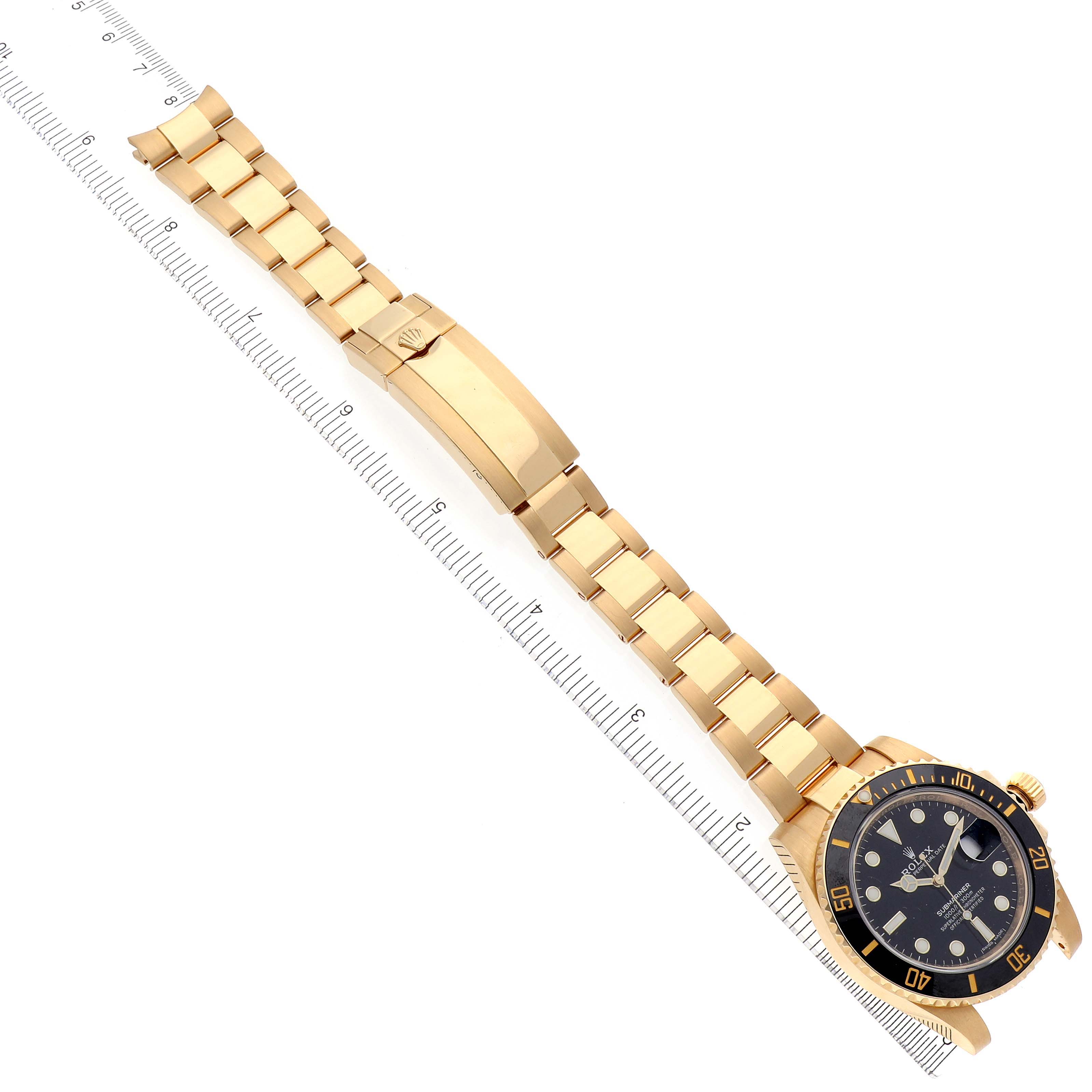 The image shows a Rolex Submariner 116618 Men
s Yellow Gold Black Dial 116618 Men
s Yellow Gold Black Dial model watch laid flat with its strap extended and a ruler for size reference.