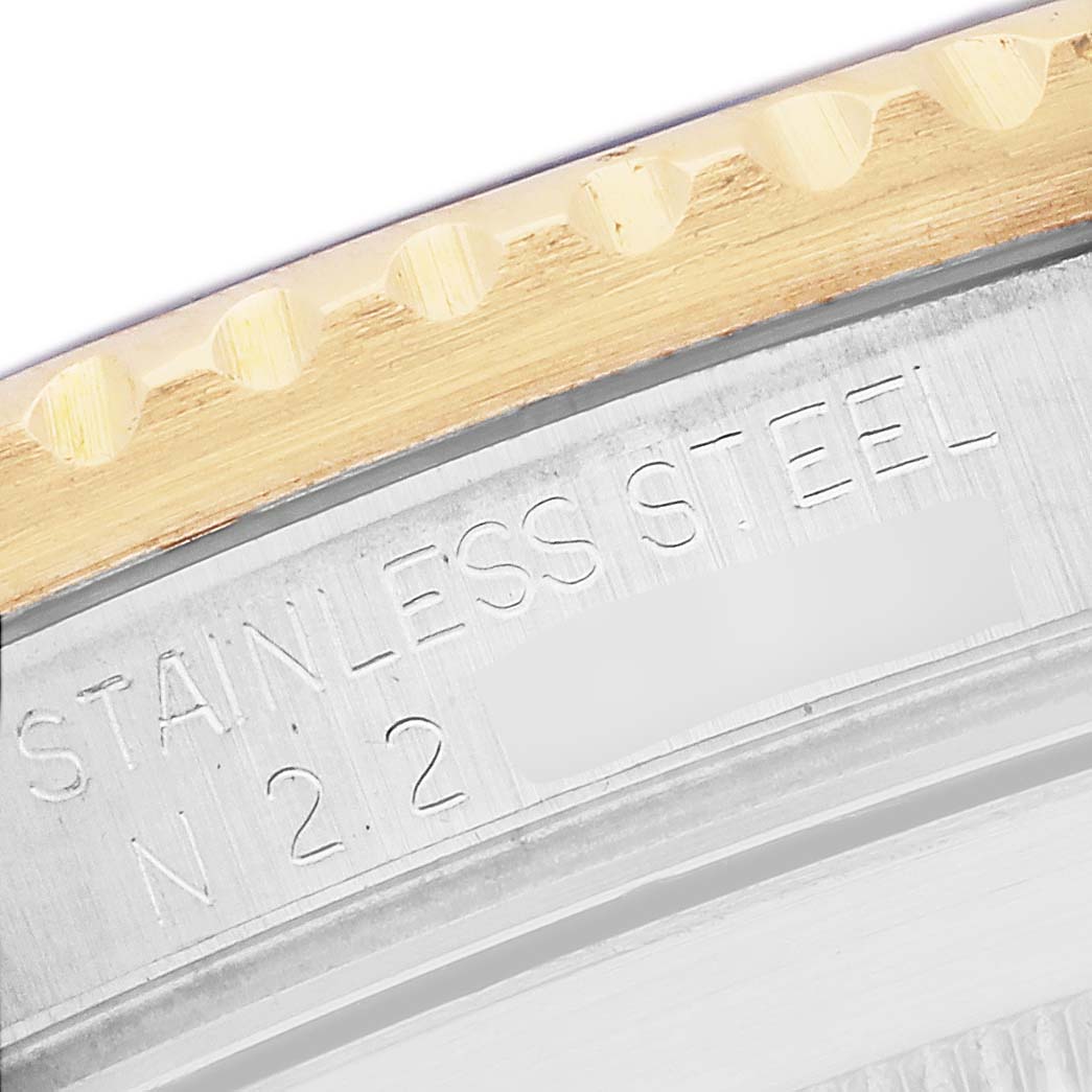 The image shows the edge of the Rolex Submariner 16613 Men
s Steel and Gold (two tone) Blue Dial
s bezel and side, highlighting the "STAINLESS STEEL" engraving.