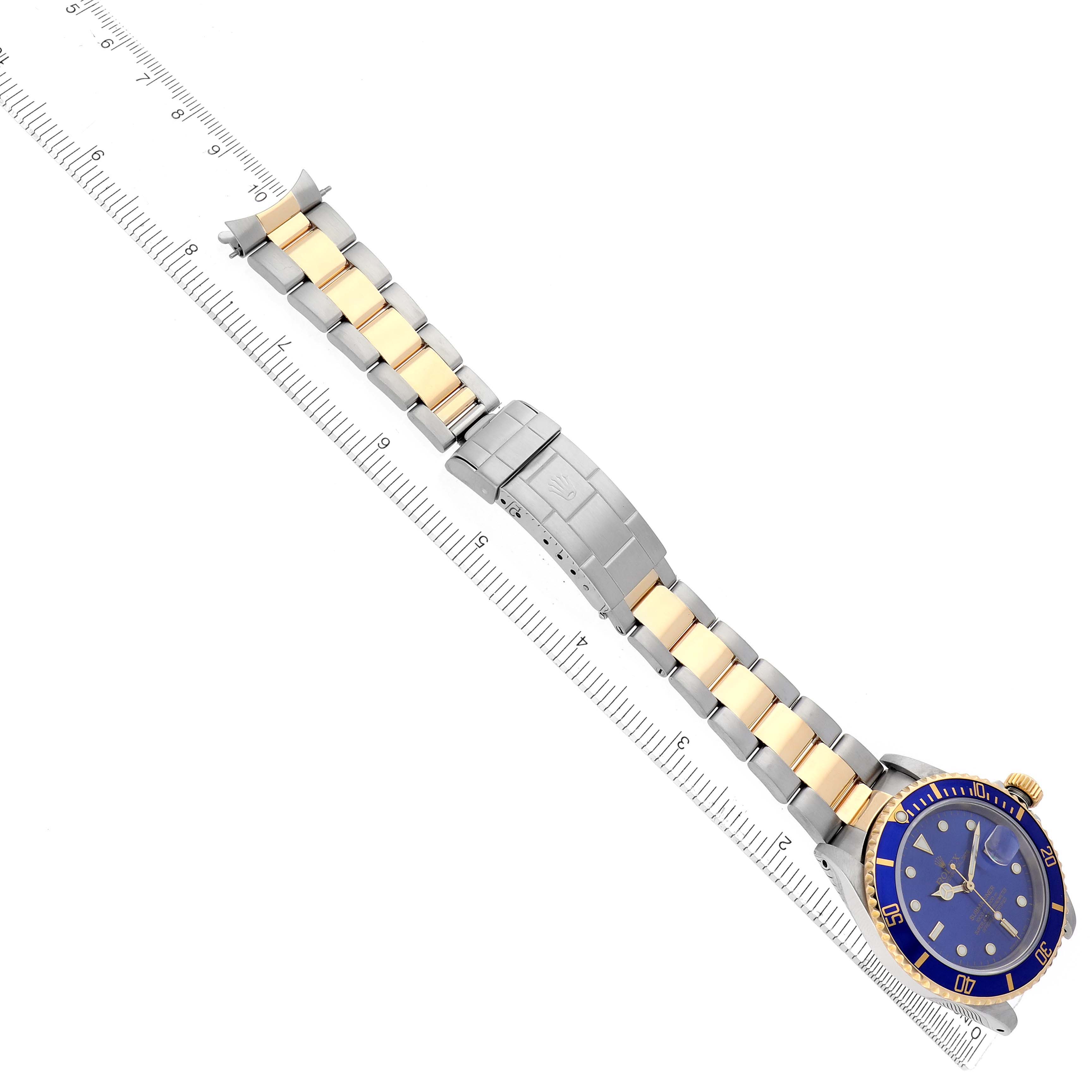 The image shows a top-down view of a Rolex Submariner 16613 Men
s Steel and Gold (two tone) Blue Dial watch, highlighting its blue dial, gold and silver bracelet, and clasp.