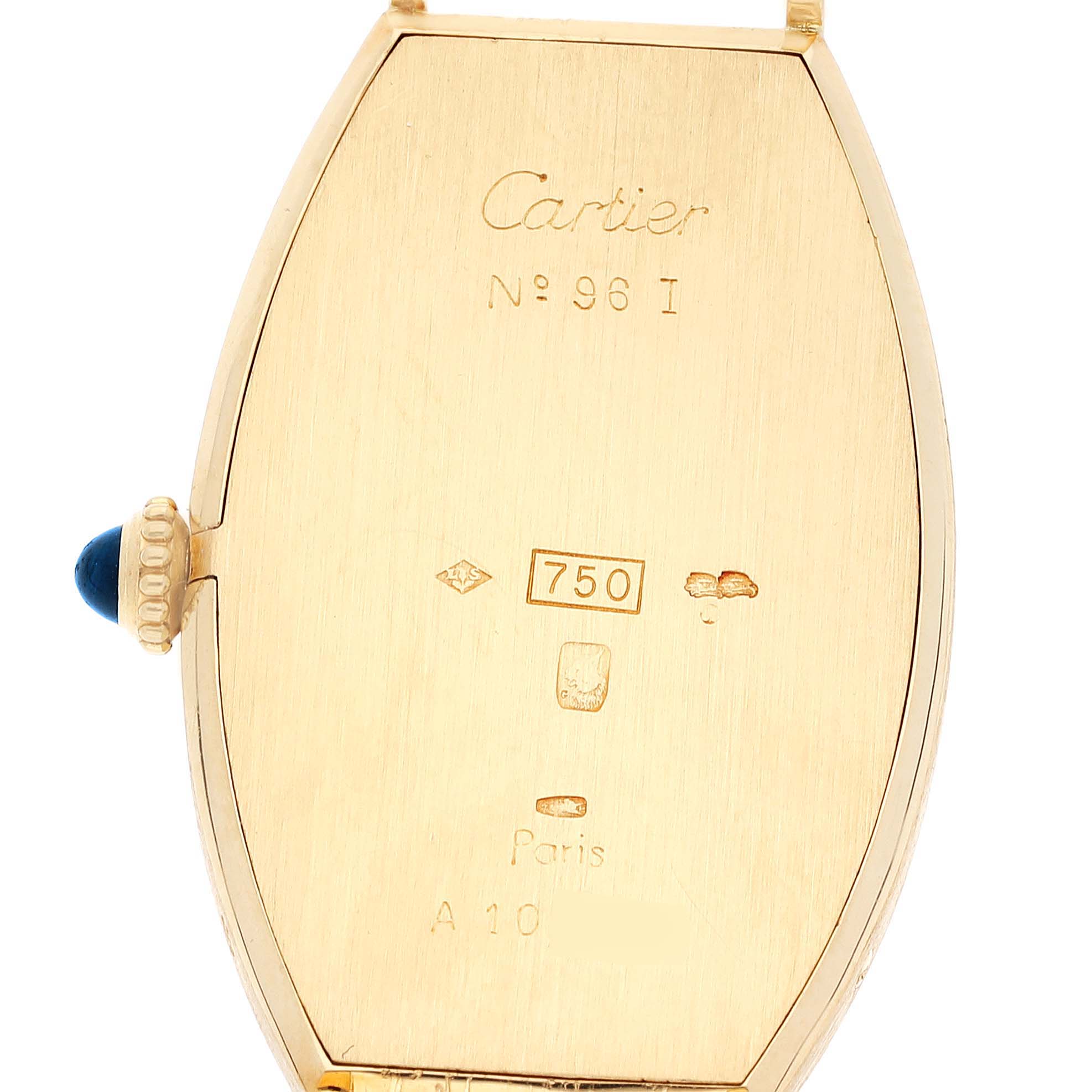 This image shows the back casing of a Cartier Tonneau Women
s Yellow Gold Silver Dial Women
s Yellow Gold Silver Dial model watch, highlighting its engravings and crown with a blue gemstone.
