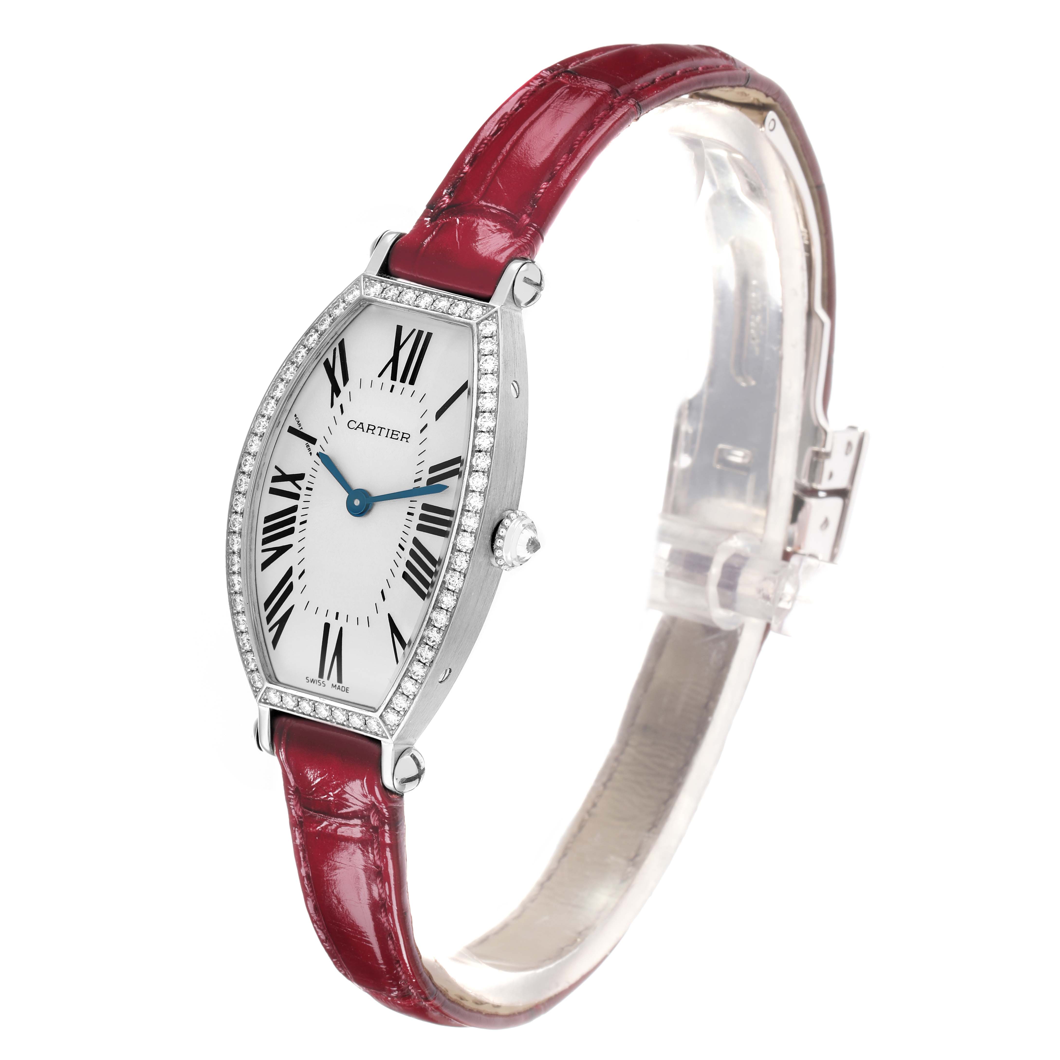 The Cartier Tonneau WE400131 Women
s White Gold Silver Dial watch is shown from a three-quarter angle, highlighting its red strap, elongated dial, and side crown.