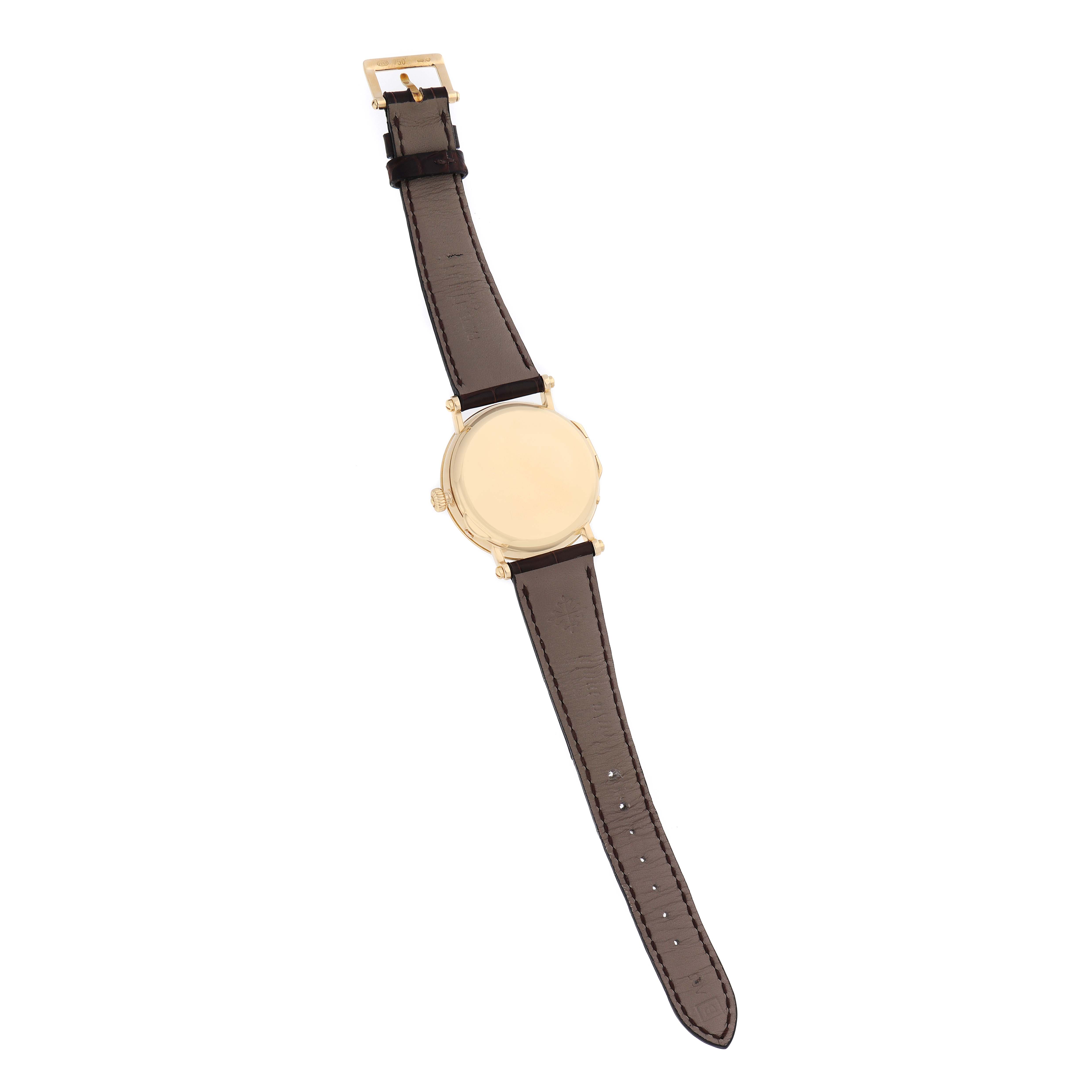 The Patek Philippe Complications 5054 Men
s Yellow Gold White Dial watch is shown from the back, highlighting the case back and brown leather strap.