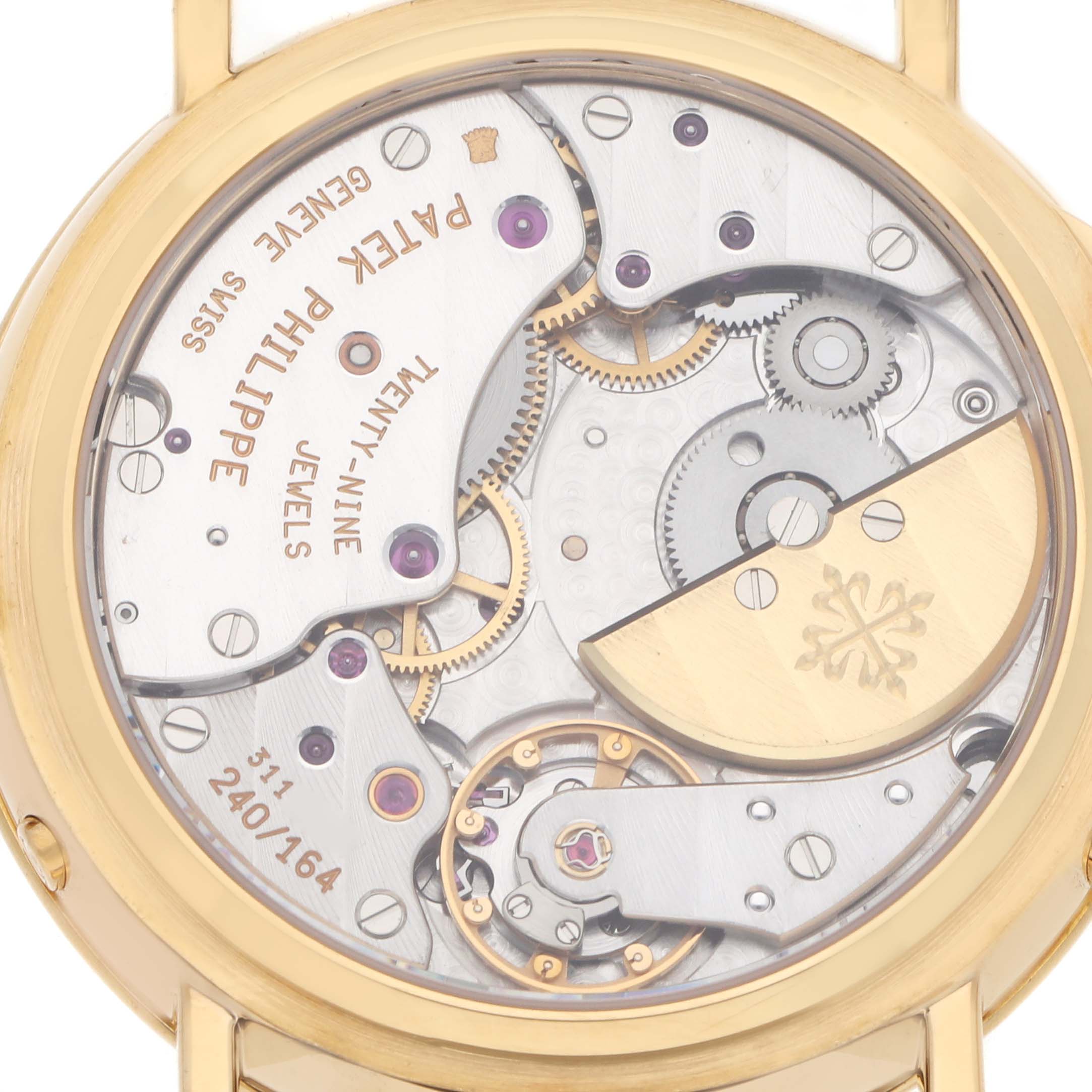 The image shows the back view of a Patek Philippe Complications 5054 Men
s Yellow Gold White Dial watch, highlighting its movement and intricate mechanics.