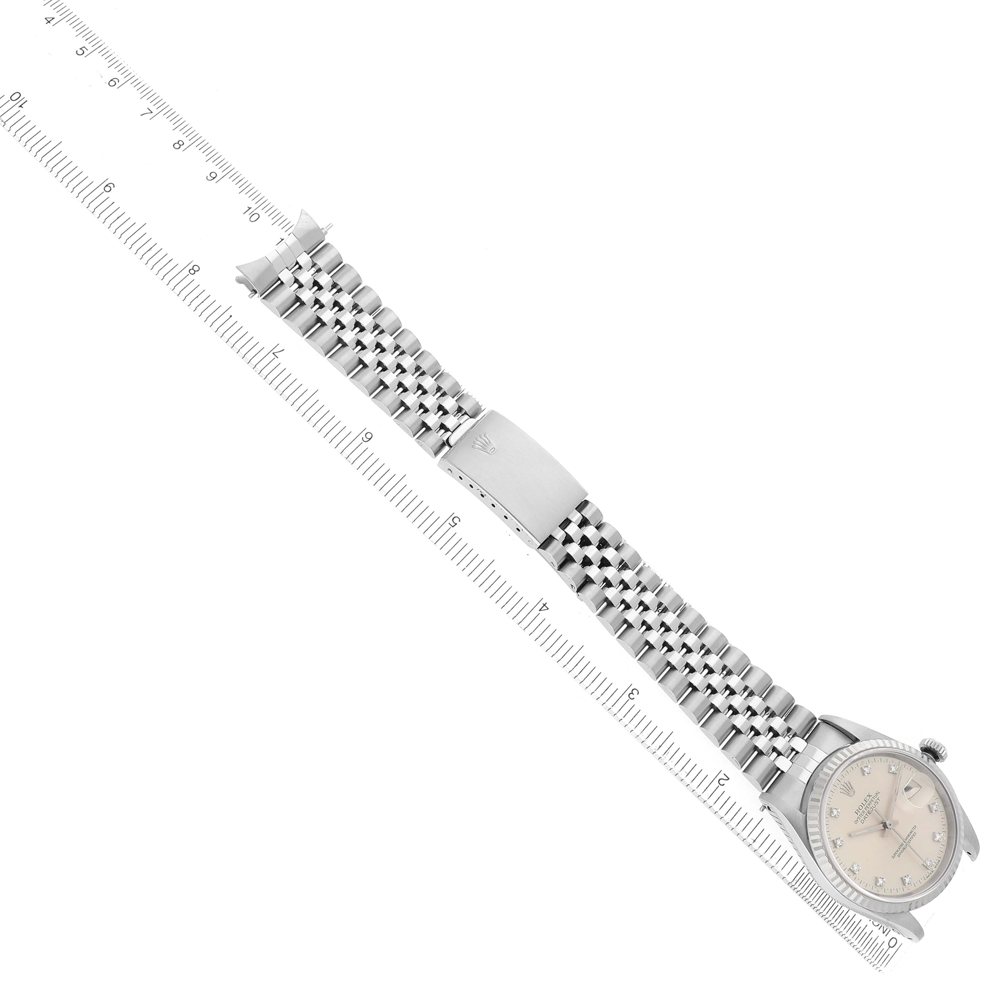 The image shows a Rolex Datejust 16234 Men
s Stainless Steel Silver Dial watch at an angle, highlighting its face, bezel, Jubilee bracelet, and clasp beside a ruler.