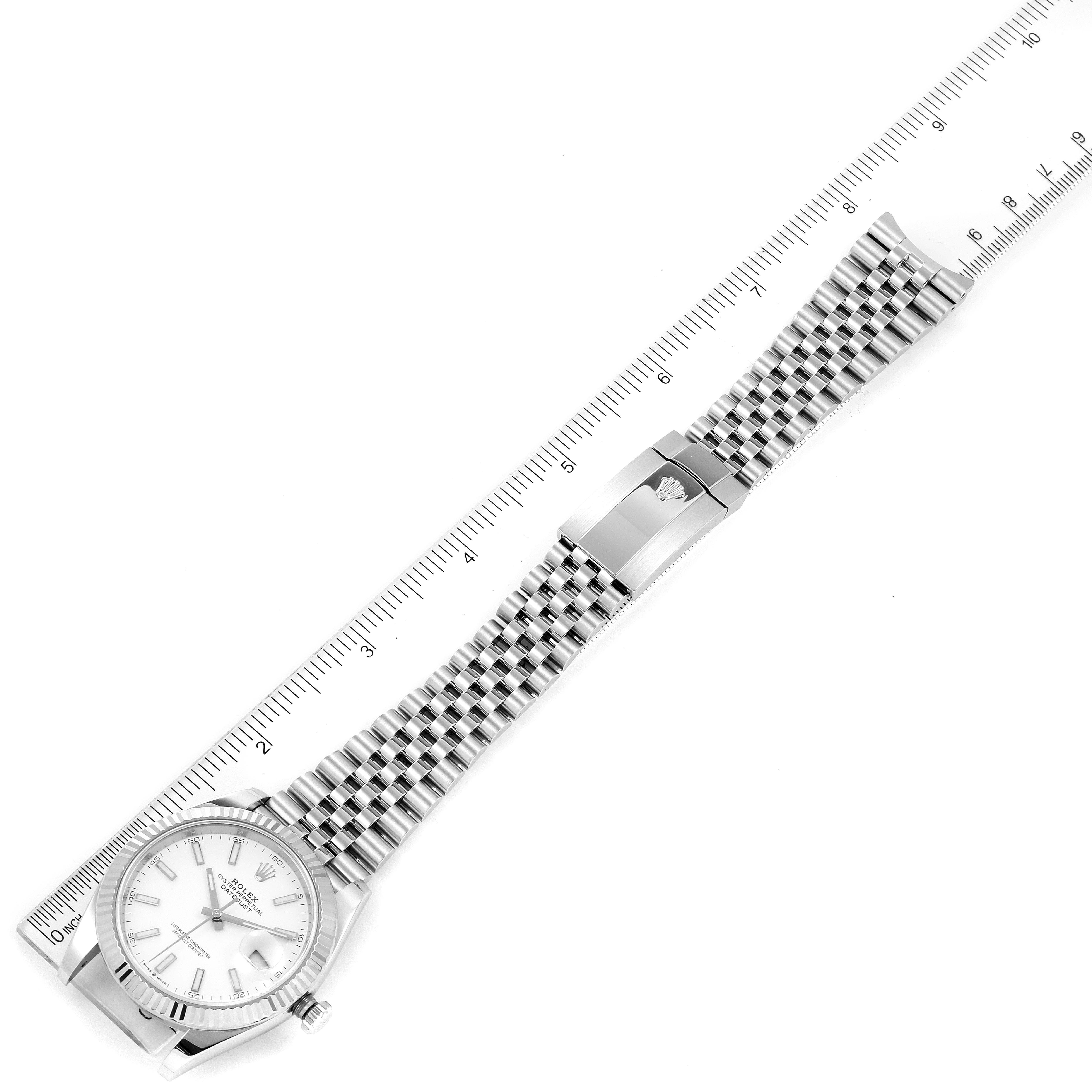 The image shows a Rolex Datejust 41 126334 Men
s Stainless Steel White Dial 126334 Men
s Stainless Steel White Dial watch laid flat next to a ruler, showcasing the dial, case, and bracelet clasp.