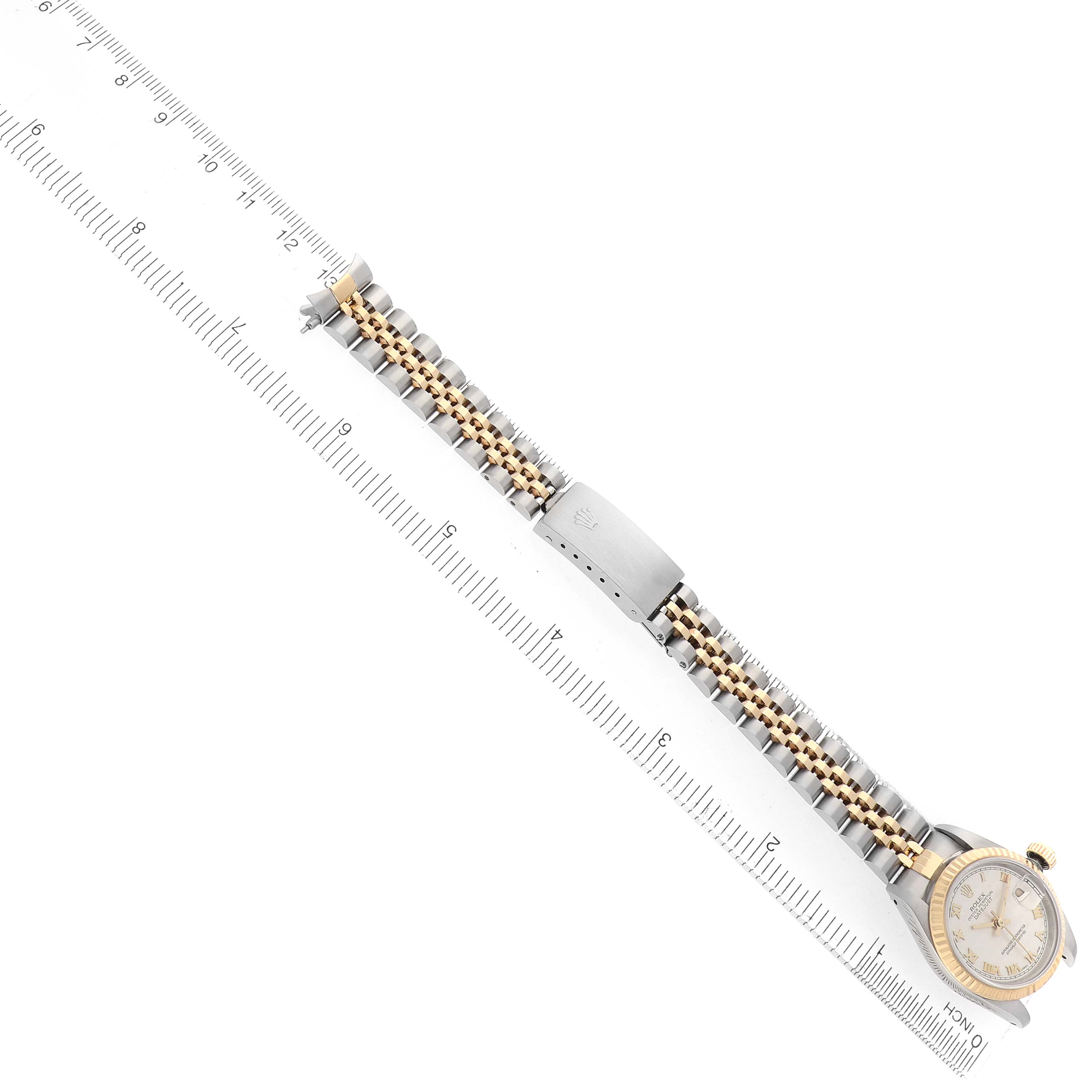 The Rolex Datejust 69173 Women
s Steel and Gold (two tone) Silver Dial watch is shown from an overhead angle, displaying its full bracelet and clasp alongside a ruler for scale.