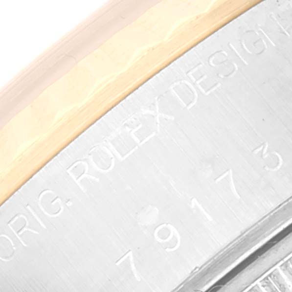 The image shows a close-up of the side of a Rolex Datejust 79173 Women's Steel and Gold (two tone) Champagne Dial 79173 Women's Steel and Gold (two tone) Champagne Dial watch with engraved text and part of the bezel.