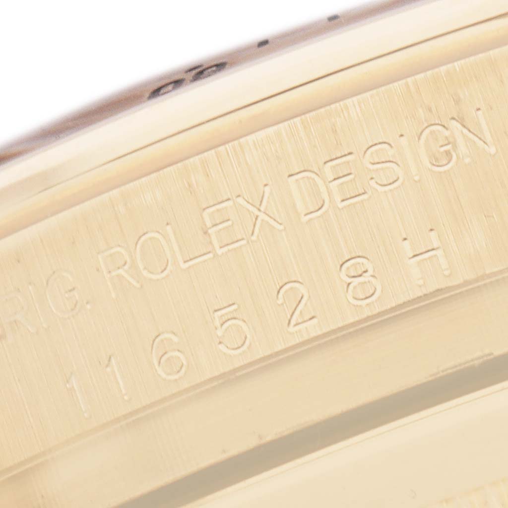 The image shows an engraved side of the case of a Rolex Daytona 116528 Men
s Yellow Gold Silver Dial, displaying the model and design number.