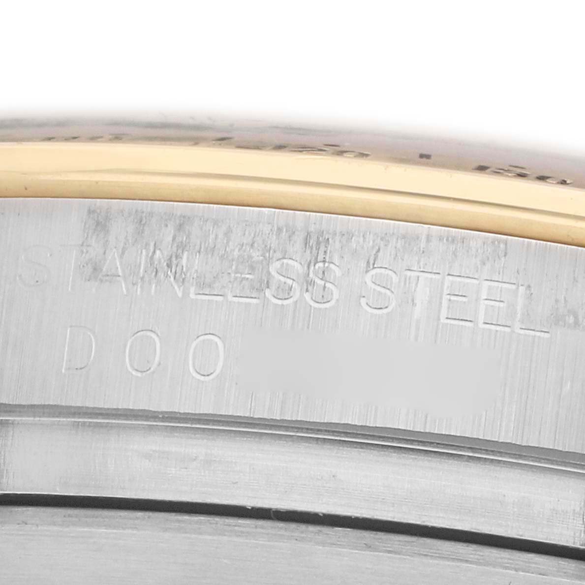 The image shows a close-up of the edge of the Rolex Daytona 116523 Men
s Steel and Gold (two tone) White Dial
s stainless steel case with engraved text.