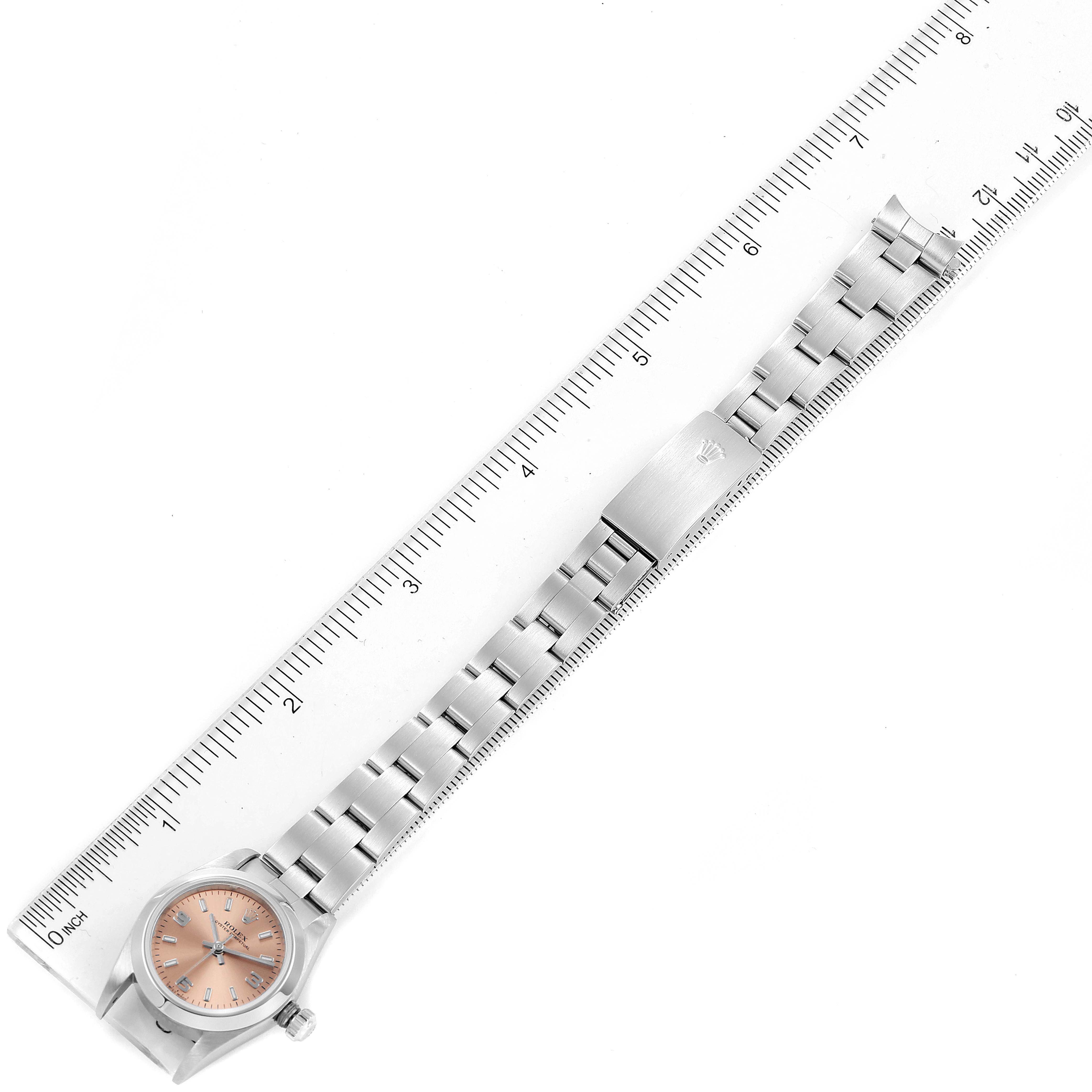 The image shows a Rolex Oyster Perpetual 76080 Women's Stainless Steel Pink Dial 76080 Women's Stainless Steel Pink Dial watch laid flat next to a ruler, displaying the face, band, and clasp from a top-down angle.