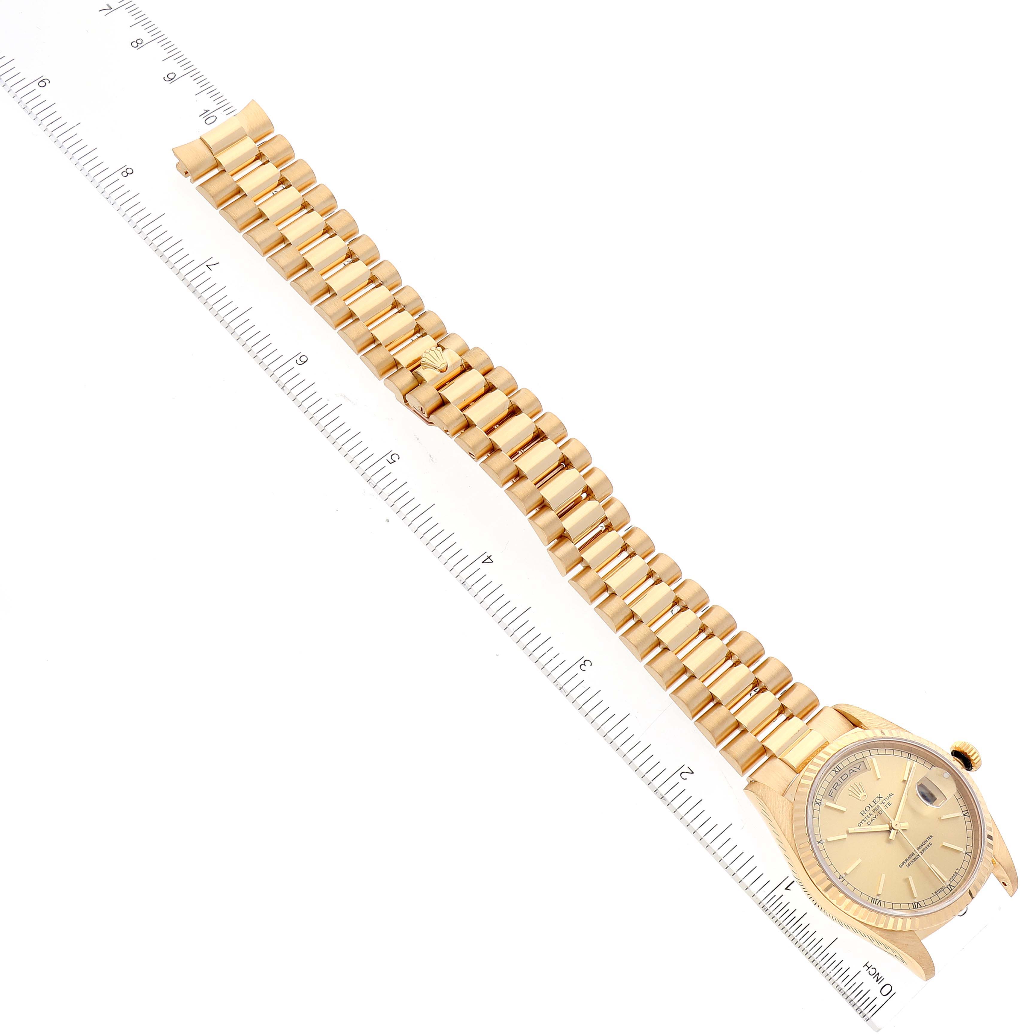The image shows a Rolex President 18238 Men
s Yellow Gold Champagne Dial 18238 Men
s Yellow Gold Champagne Dial model watch laid flat with its bracelet extended along a ruler for measurement.