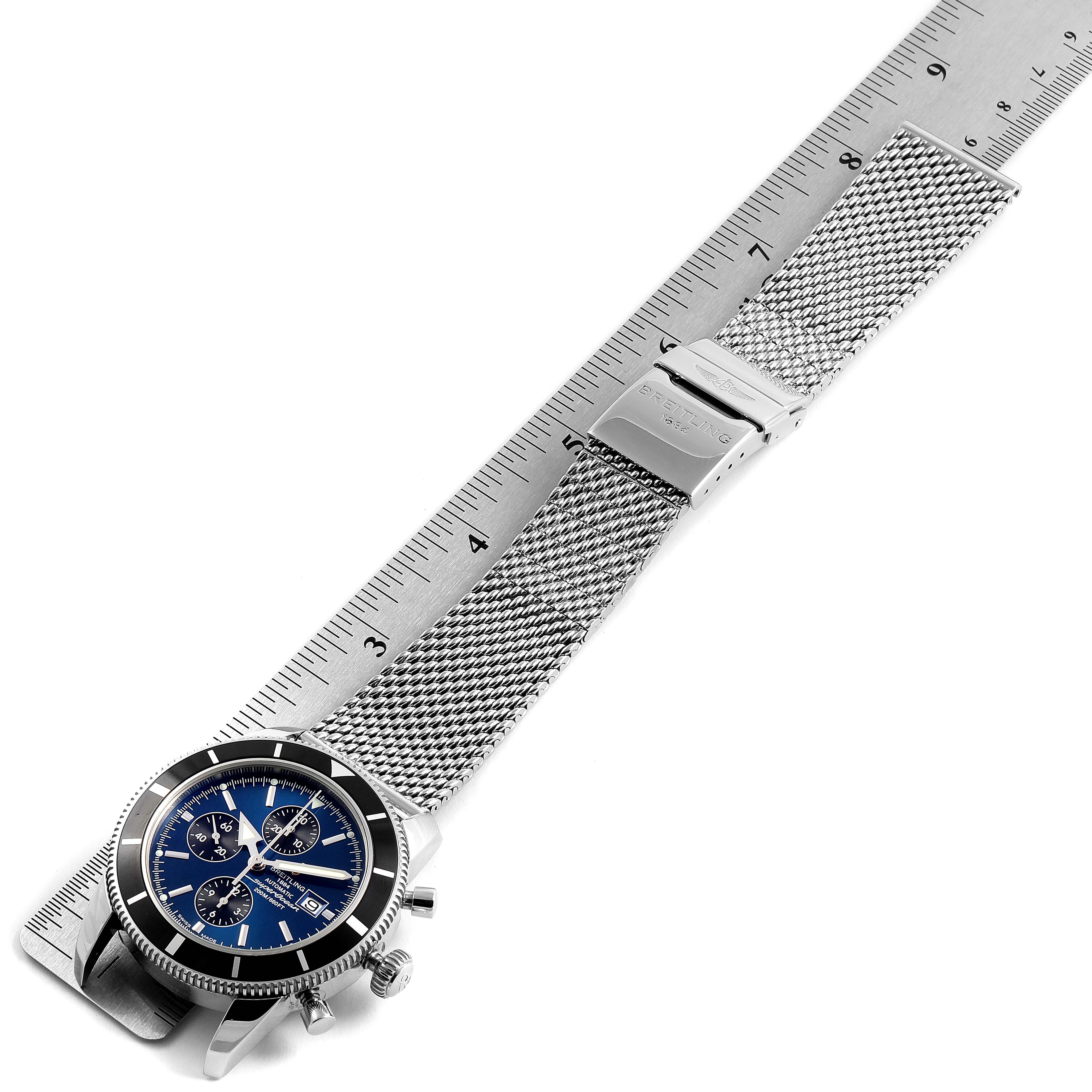 The image shows a side angle view of a Breitling Superocean A13320 Men's Stainless Steel Blue Dial A13320 Men's Stainless Steel Blue Dial watch with a stainless steel mesh band and ruler for scale.