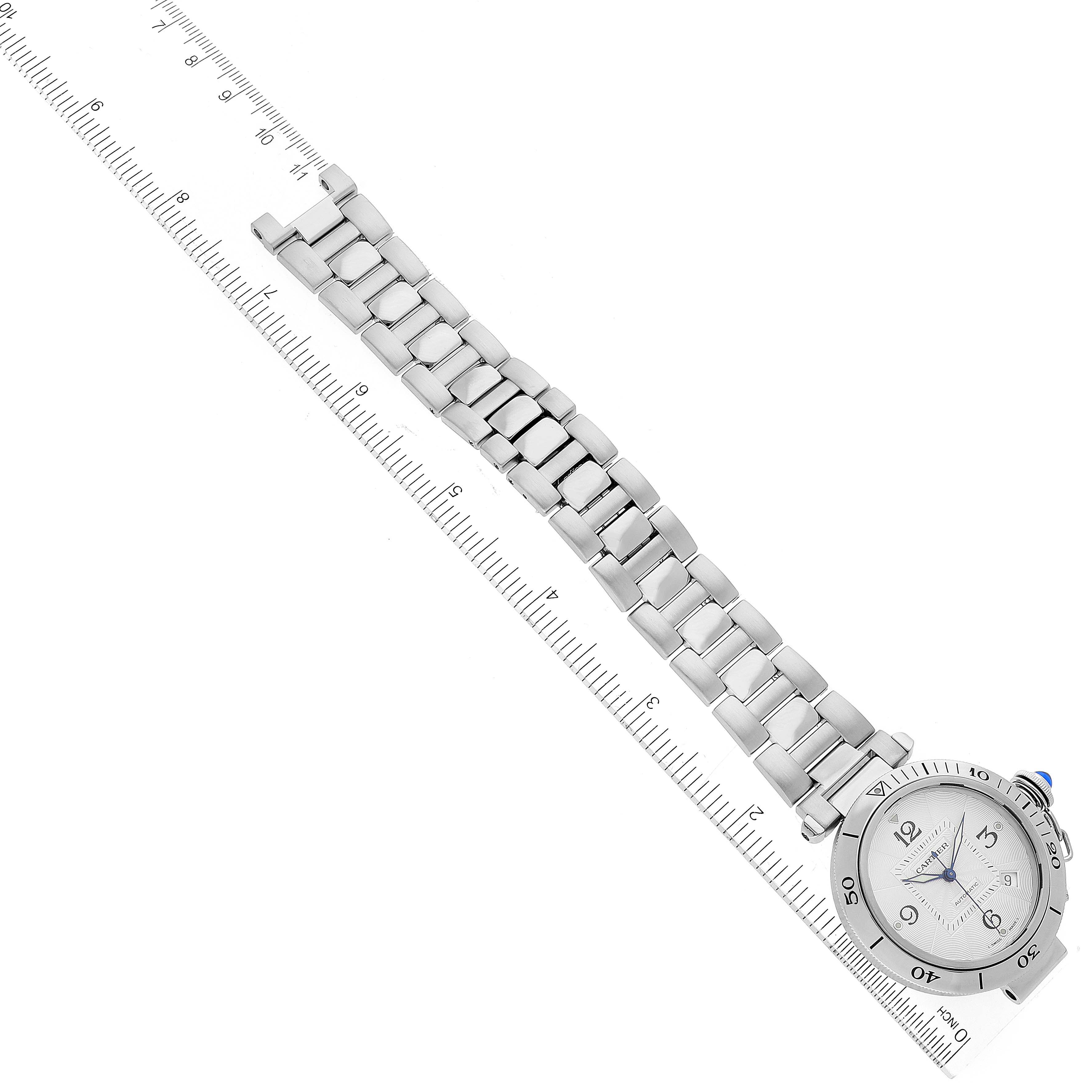 The Cartier Pasha W31040H3 Men's Stainless Steel Silver Dial W31040H3 Men's Stainless Steel Silver Dial watch is shown from a top-down angle, displaying its face and metal bracelet alongside a ruler for scale.