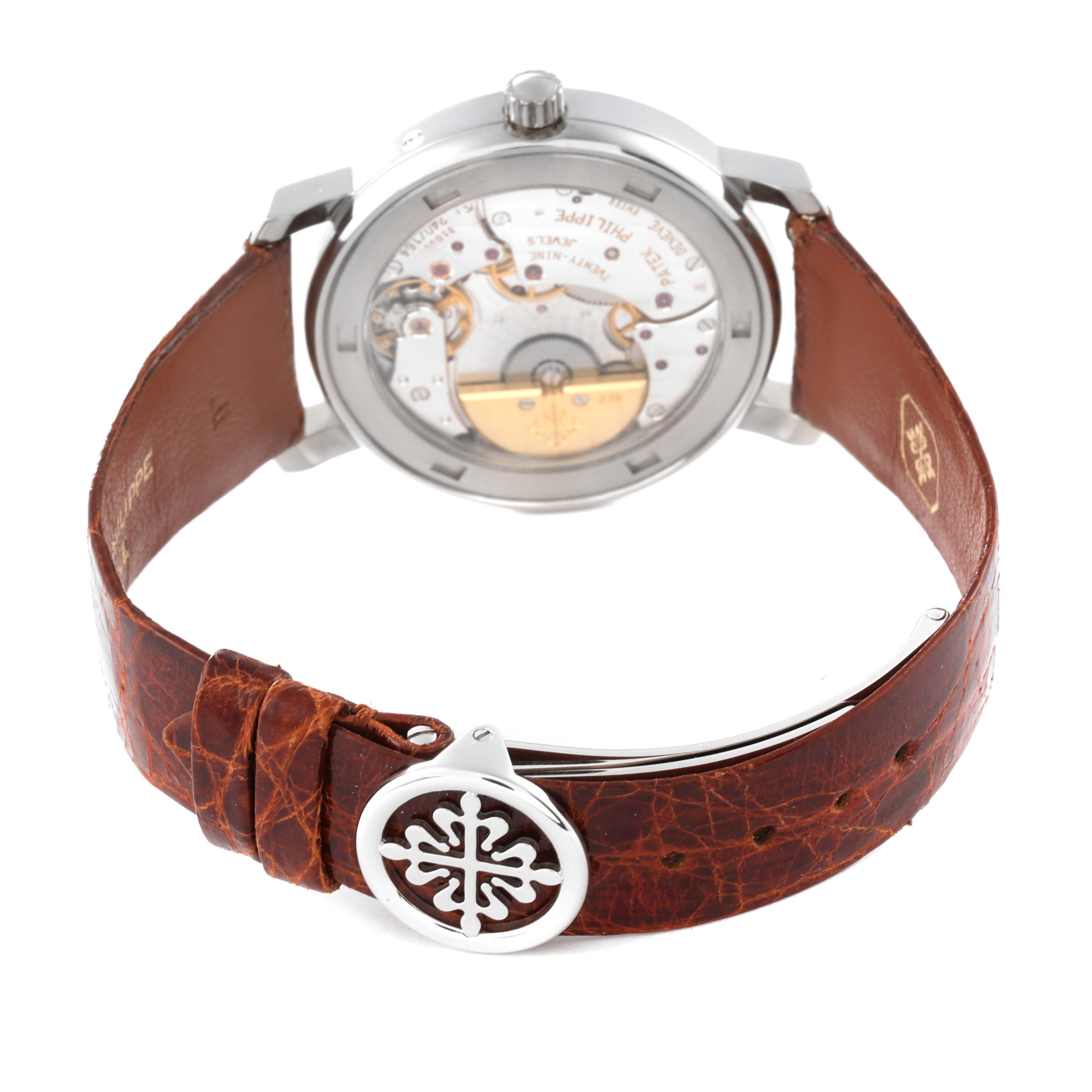The image shows the back of a Patek Philippe Complications 5055G-001 Men
s White Gold Black Dial 5055G-001 Men
s White Gold Black Dial watch, highlighting its movement and brown leather strap.