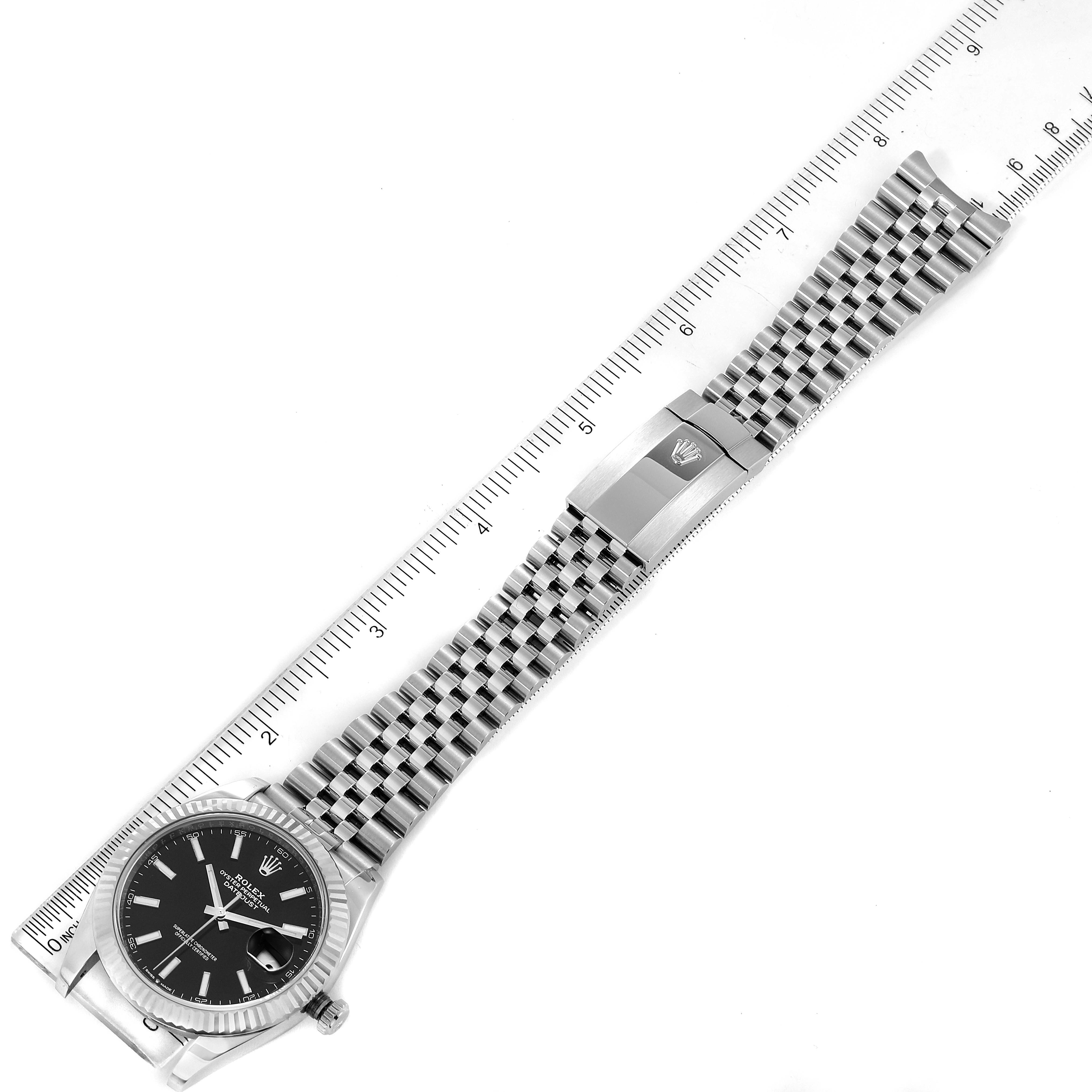 The image shows a Rolex Datejust 41 126334 Men
s Stainless Steel Black Dial 126334 Men
s Stainless Steel Black Dial watch laid flat, displaying the face, bracelet, and clasp, aligned with a ruler for scale.