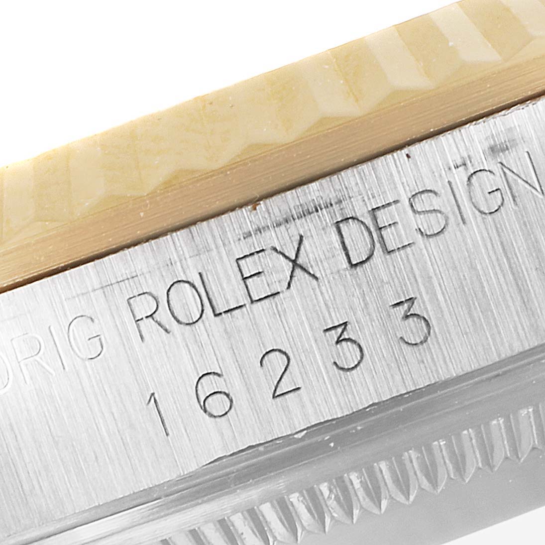 This close-up image shows the engraved model number 16233 and part of the fluted bezel on a Rolex Datejust 16233 Men's Steel and Gold (two tone) Champagne Dial 16233 Men's Steel and Gold (two tone) Champagne Dial watch.