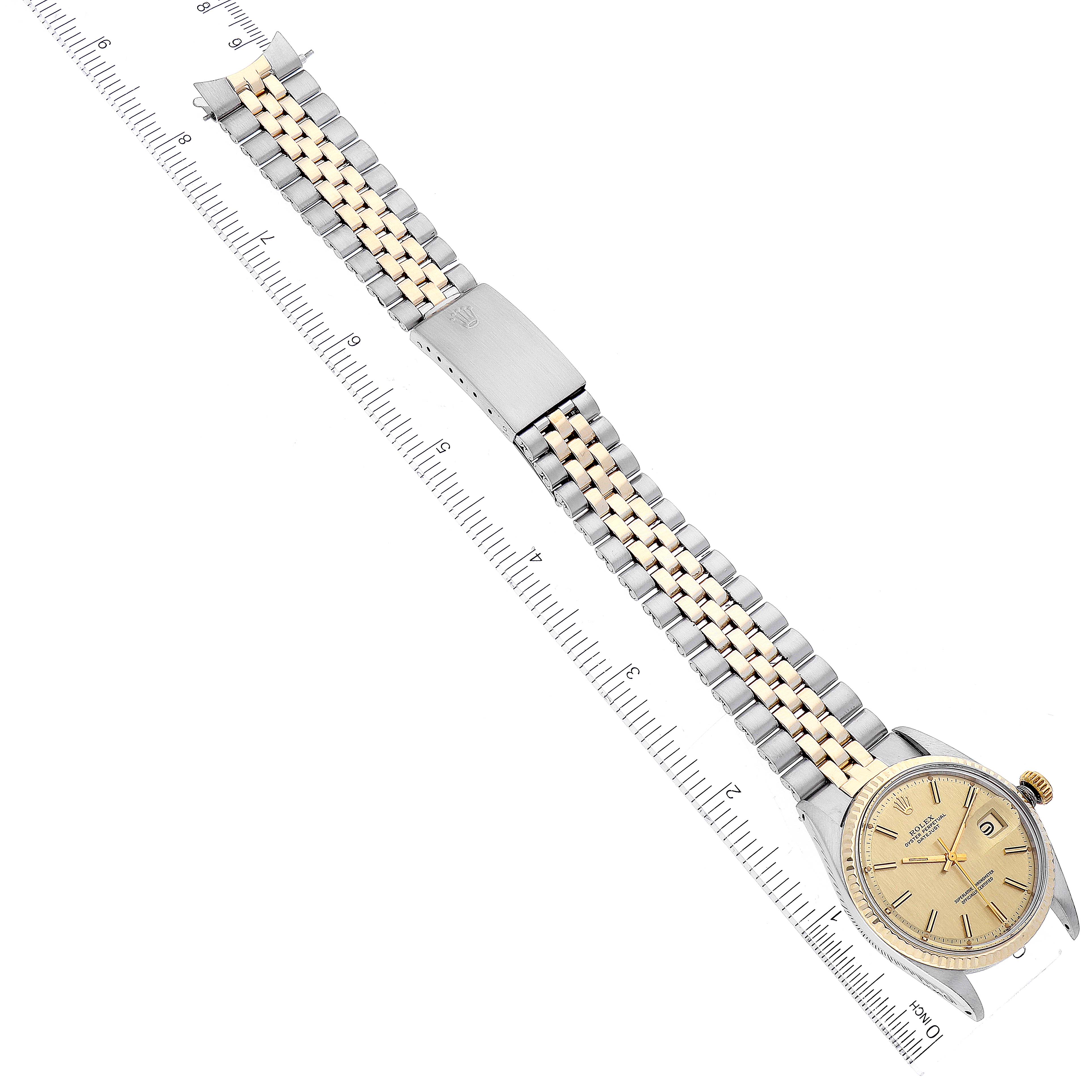 The image shows a top-down view of a Rolex Vintage Collection 1601 Men
s Steel and Gold (two tone) Champagne Dial 1601 Men
s Steel and Gold (two tone) Champagne Dial watch, highlighting the face, bracelet, and clasp against a ruler for scale.