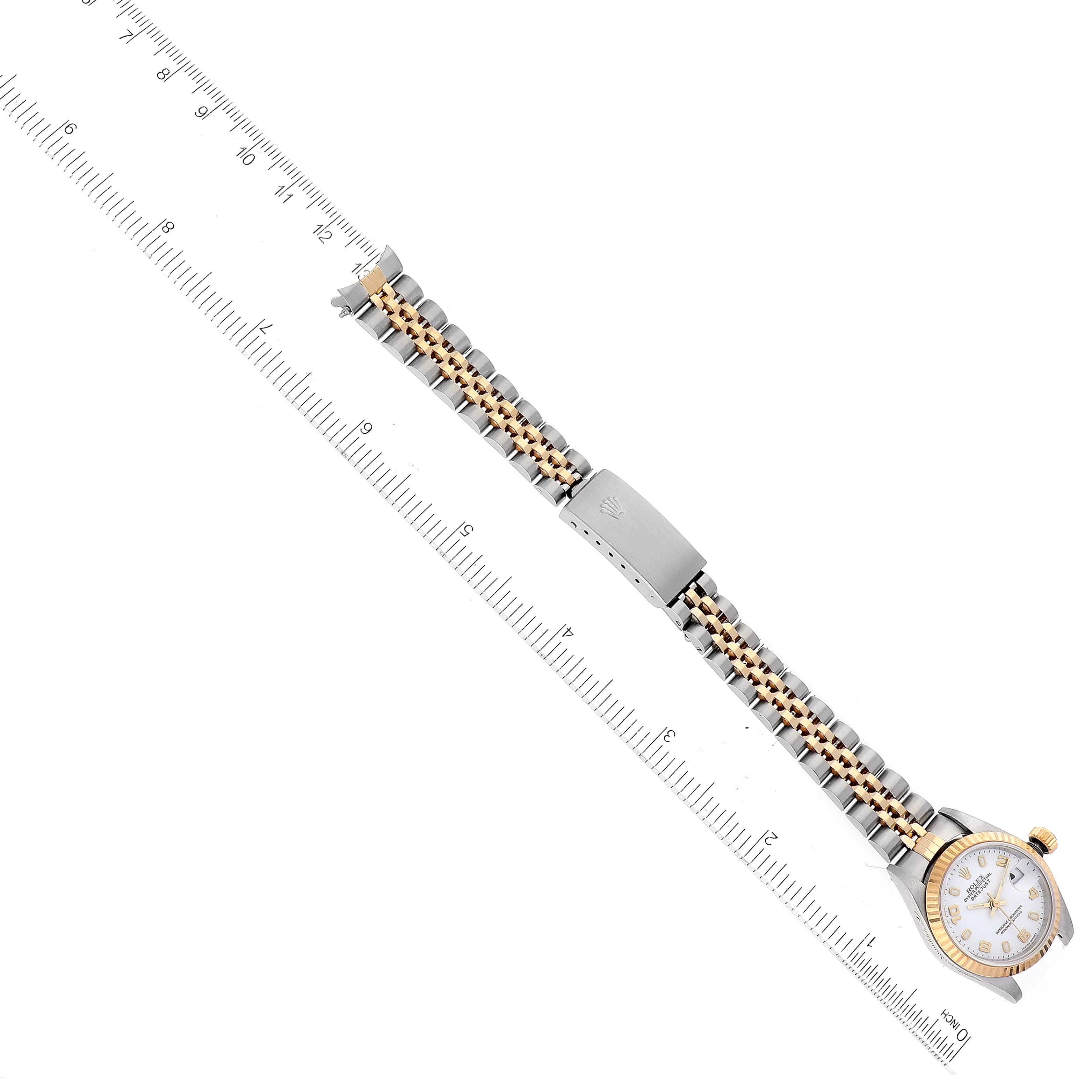 The image shows a top-down view of the Rolex Datejust 79173 Women's Steel and Gold (two tone) White Dial 79173 Women's Steel and Gold (two tone) White Dial watch, displaying the dial, bracelet, and clasp next to a ruler for scale.