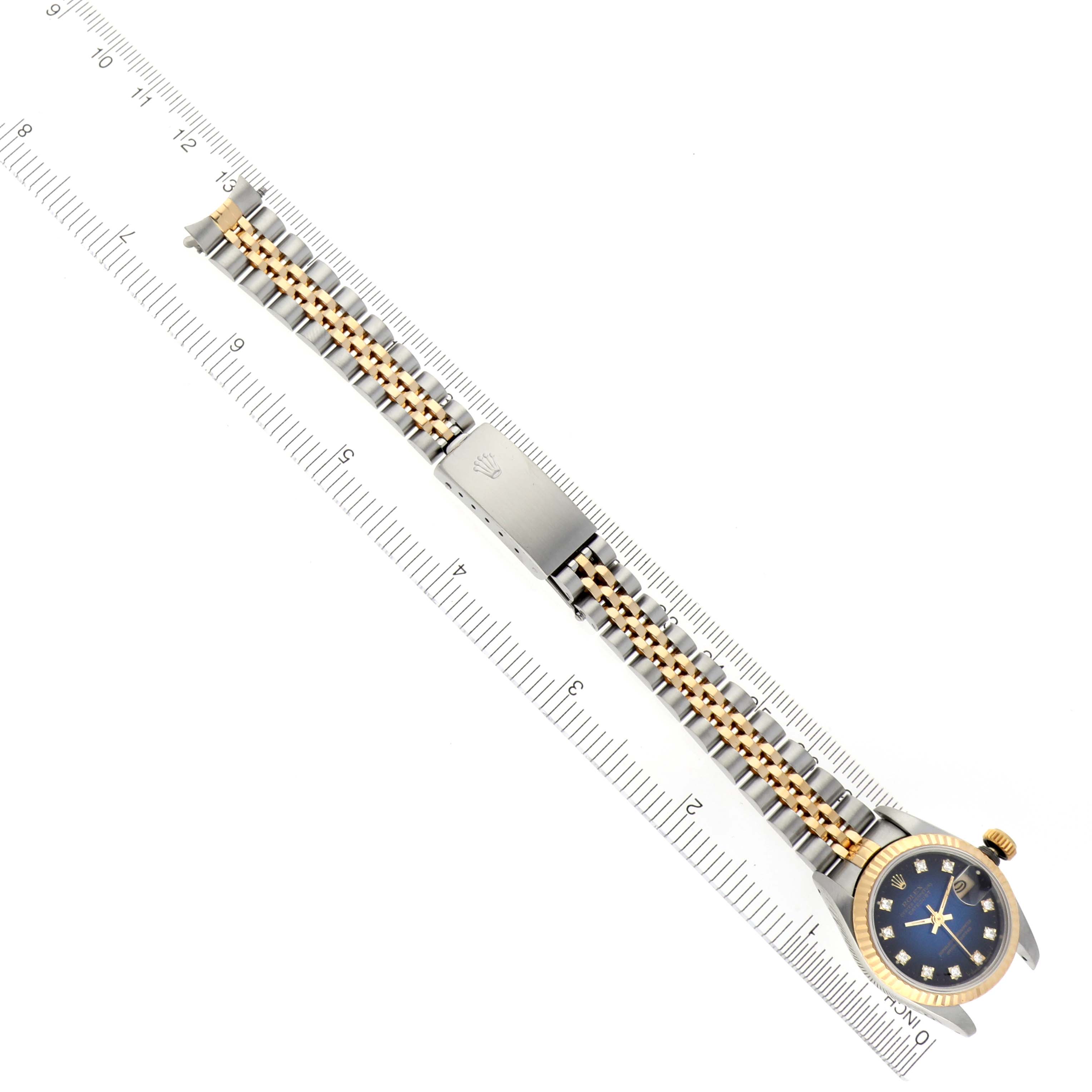 A top-down view of a Rolex Datejust 69173 Women's Steel and Gold (two tone) Blue Dial 69173 Women's Steel and Gold (two tone) Blue Dial watch showing the dial, case, bezel, crown, and jubilee bracelet with a ruler for scale.