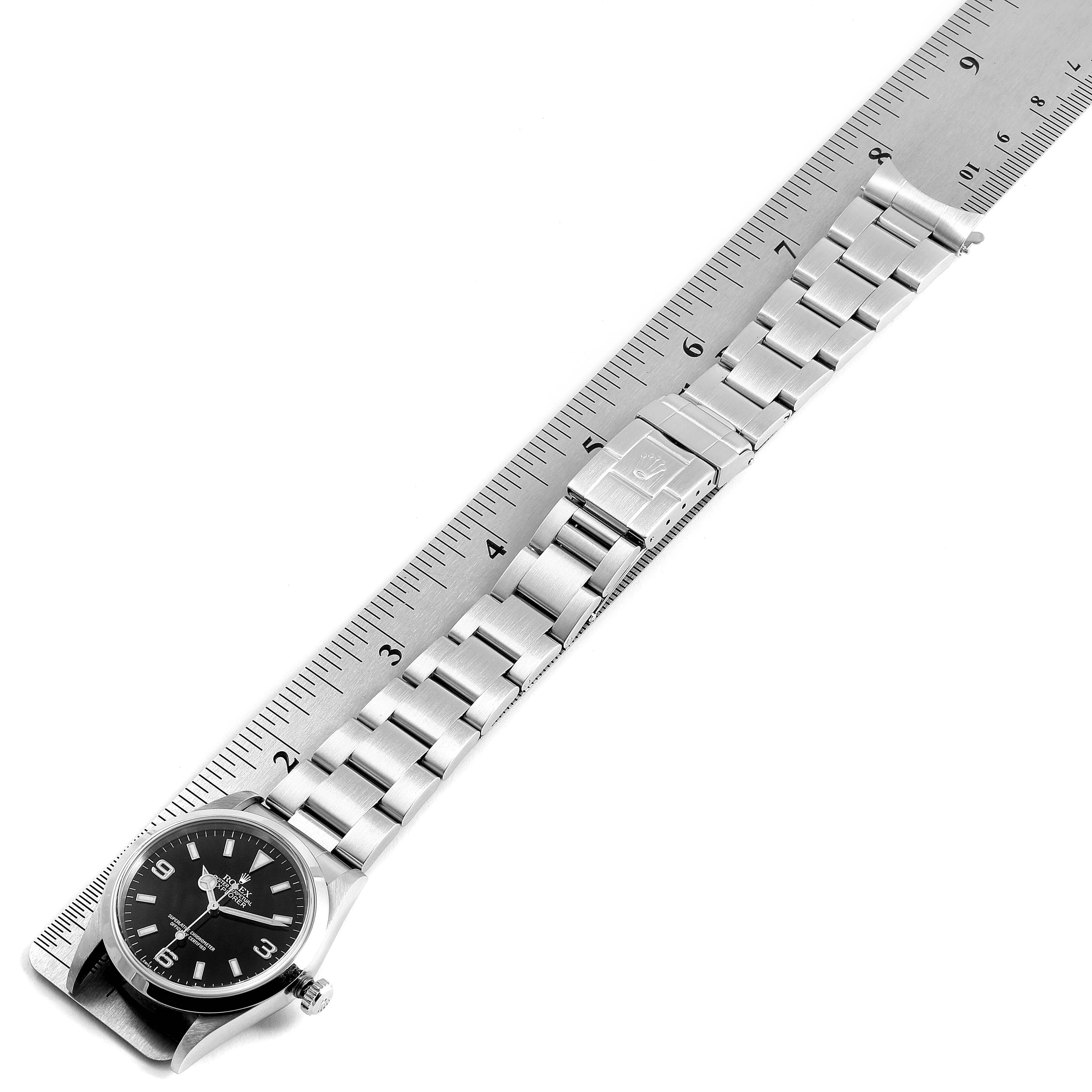 The image shows a top-down view of a Rolex Explorer 14270 Men's Stainless Steel Black Dial 14270 Men's Stainless Steel Black Dial watch, with the face, bracelet, and clasp visible, next to a ruler for scale.