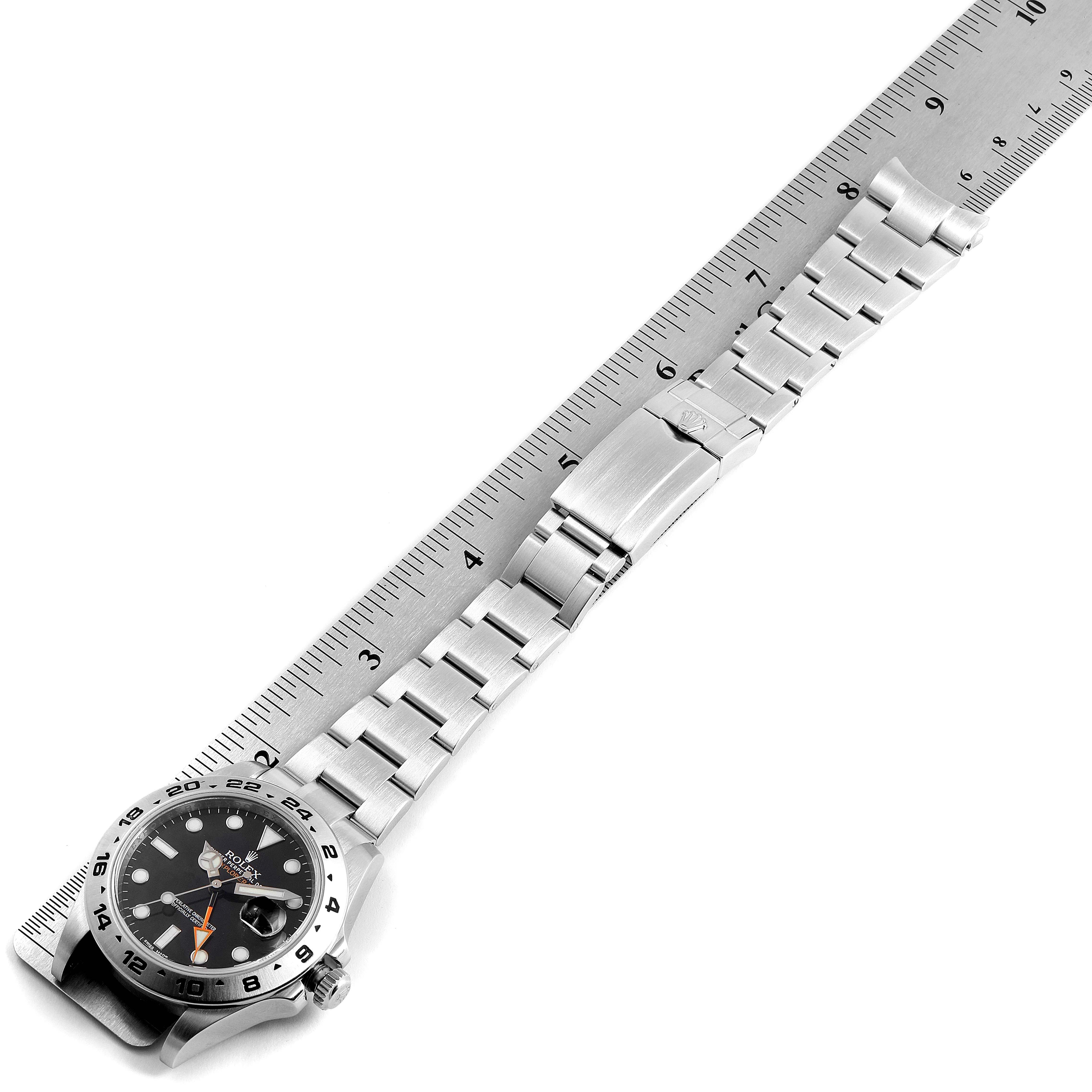 The Rolex Explorer 216570 Men's Stainless Steel Black Dial 216570 Men's Stainless Steel Black Dial watch is shown from a top-down angle, displaying the face, bezel, and metal bracelet on a ruler.