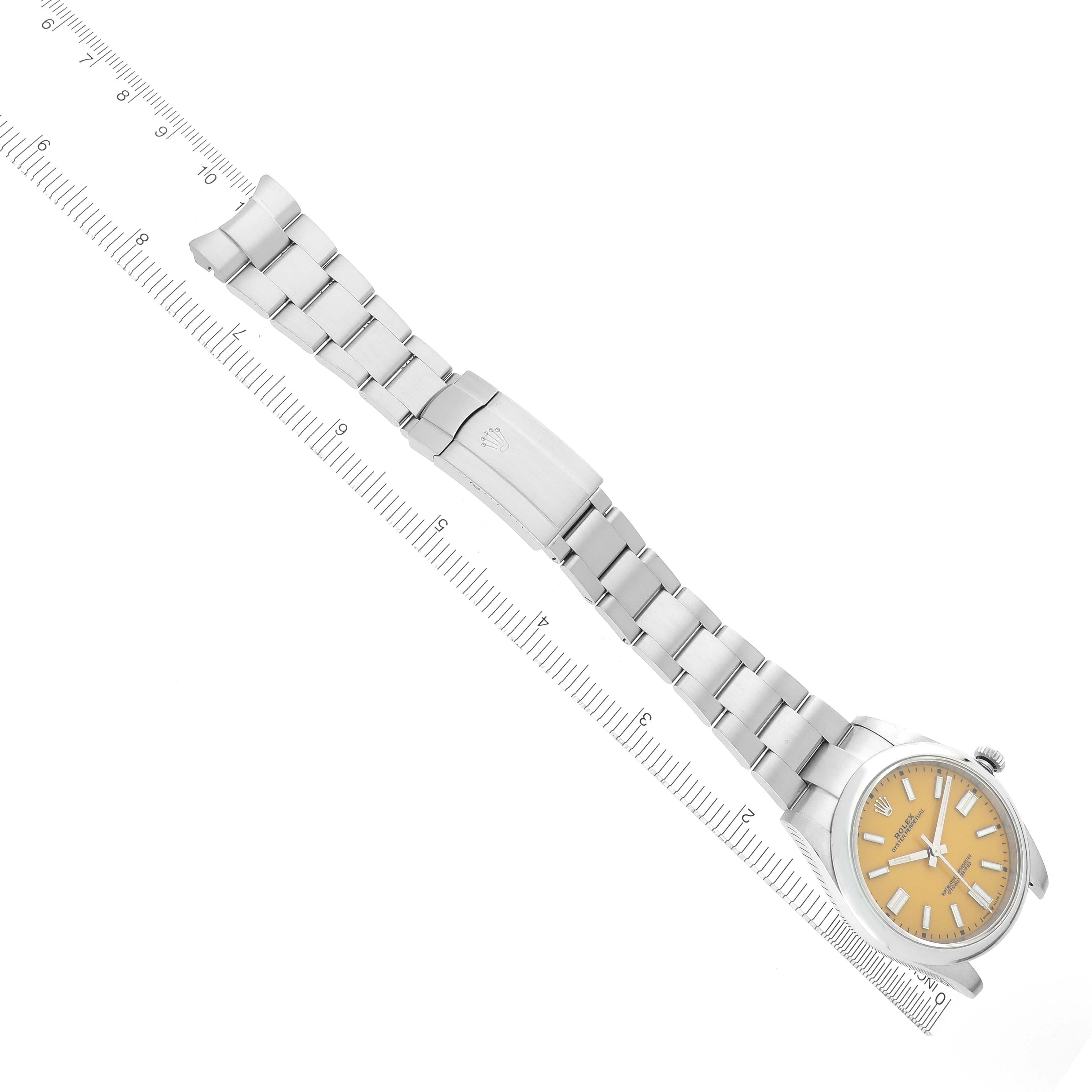 The image shows a Rolex Oyster Perpetual 124300 Men's Stainless Steel Yellow Dial 124300 Men's Stainless Steel Yellow Dial watch laid flat, highlighting its bracelet, clasp, and dial from a top-down angle.