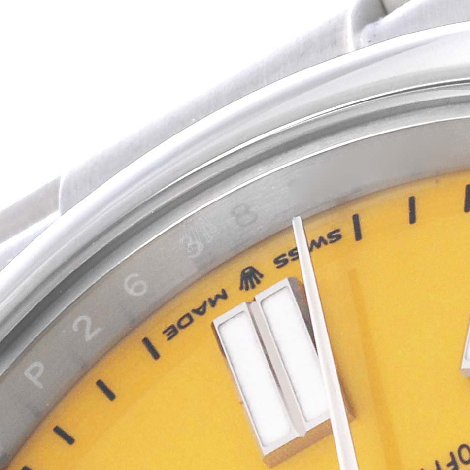 This close-up of the Rolex Oyster Perpetual 124300 Men's Stainless Steel Yellow Dial 124300 Men's Stainless Steel Yellow Dial watch shows part of the yellow dial, the edge of the case, the minute hand, and the "Swiss Made" text.