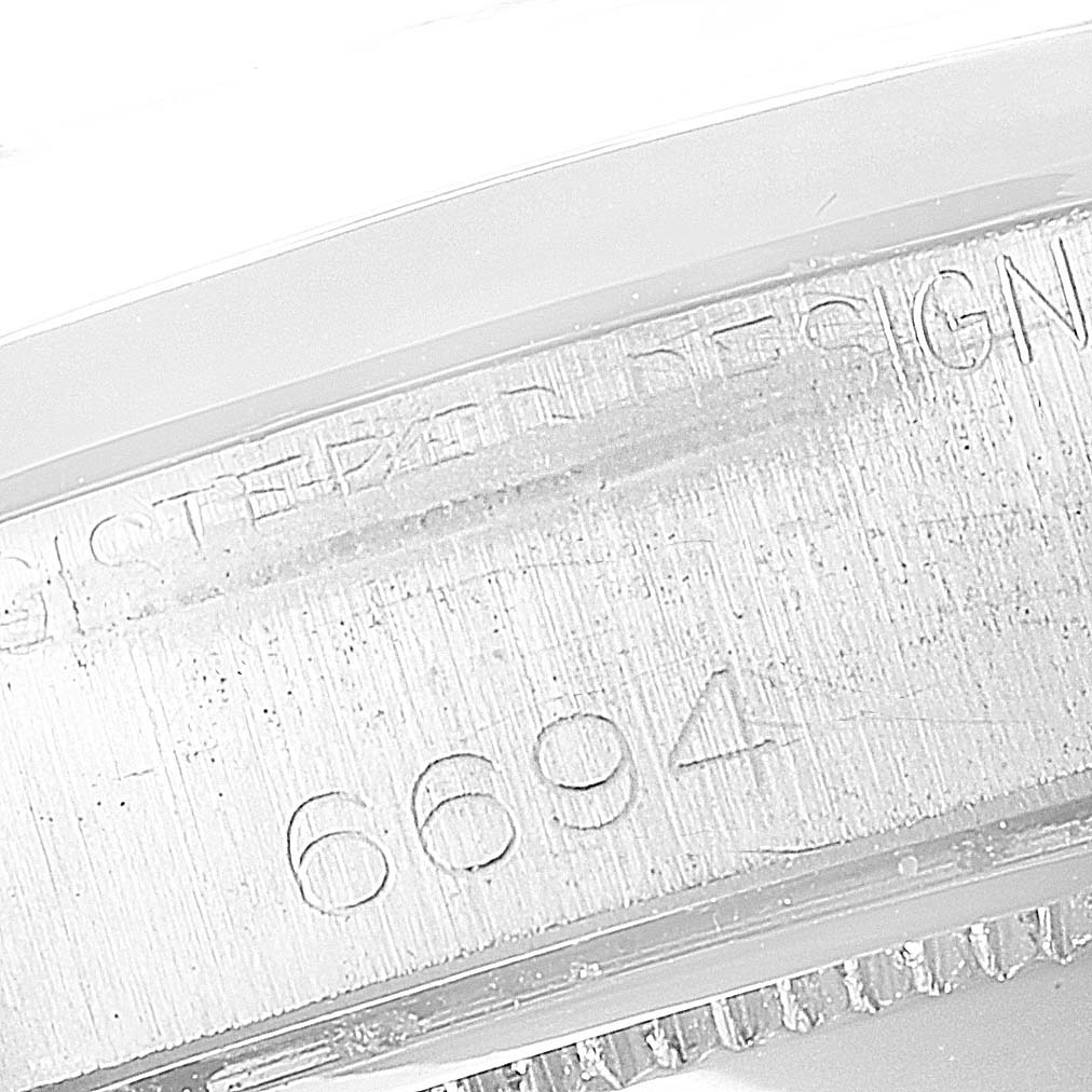 This image shows a close-up of the engraved serial number and part of the bezel on a Rolex Vintage Collection 6694 Men's Stainless Steel Silver Dial 6694 Men's Stainless Steel Silver Dial watch.
