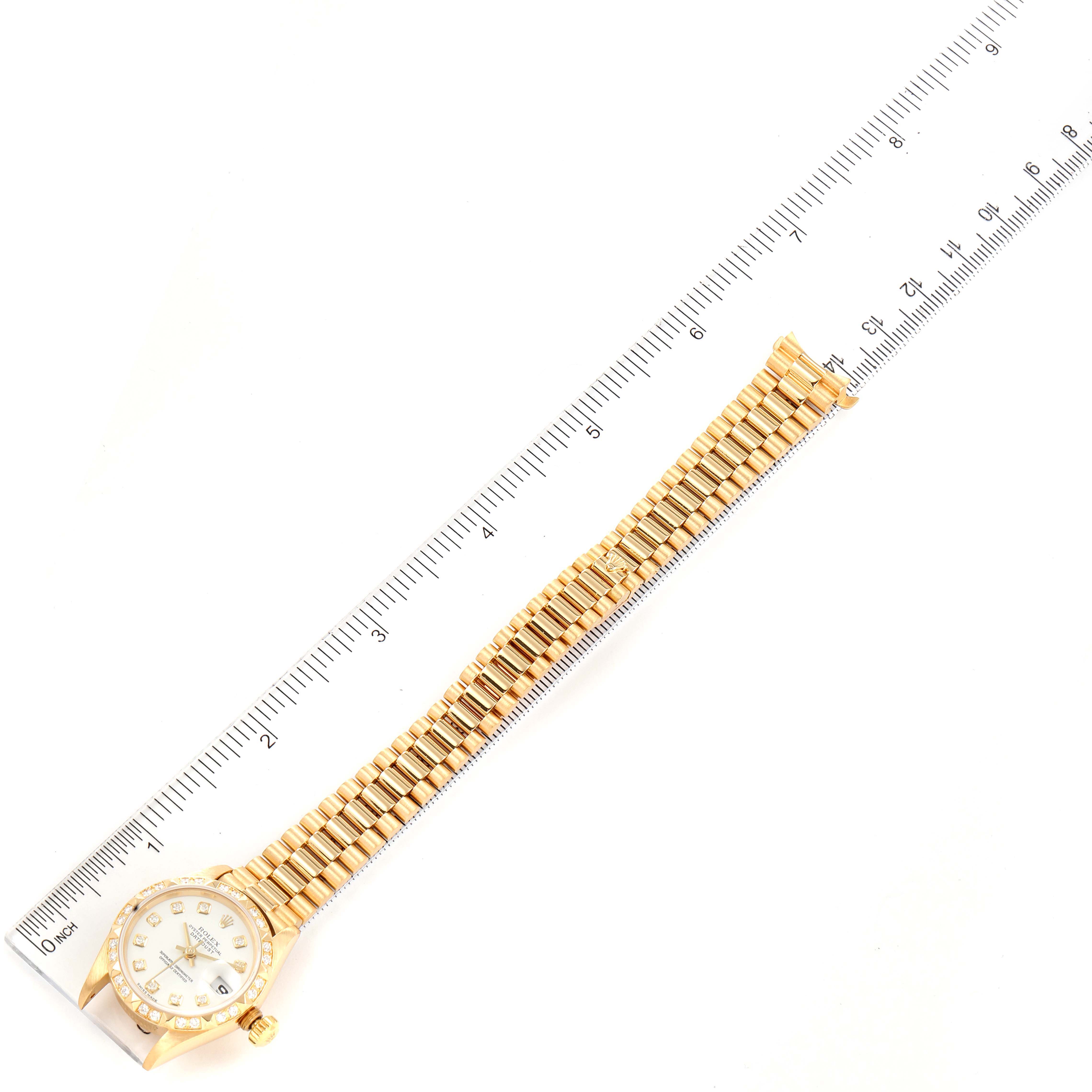 The image shows the Rolex President 79258 Women
s Yellow Gold White Dial 79258 Women
s Yellow Gold White Dial model watch laid flat with the entire bracelet and case visible, measured by a ruler.