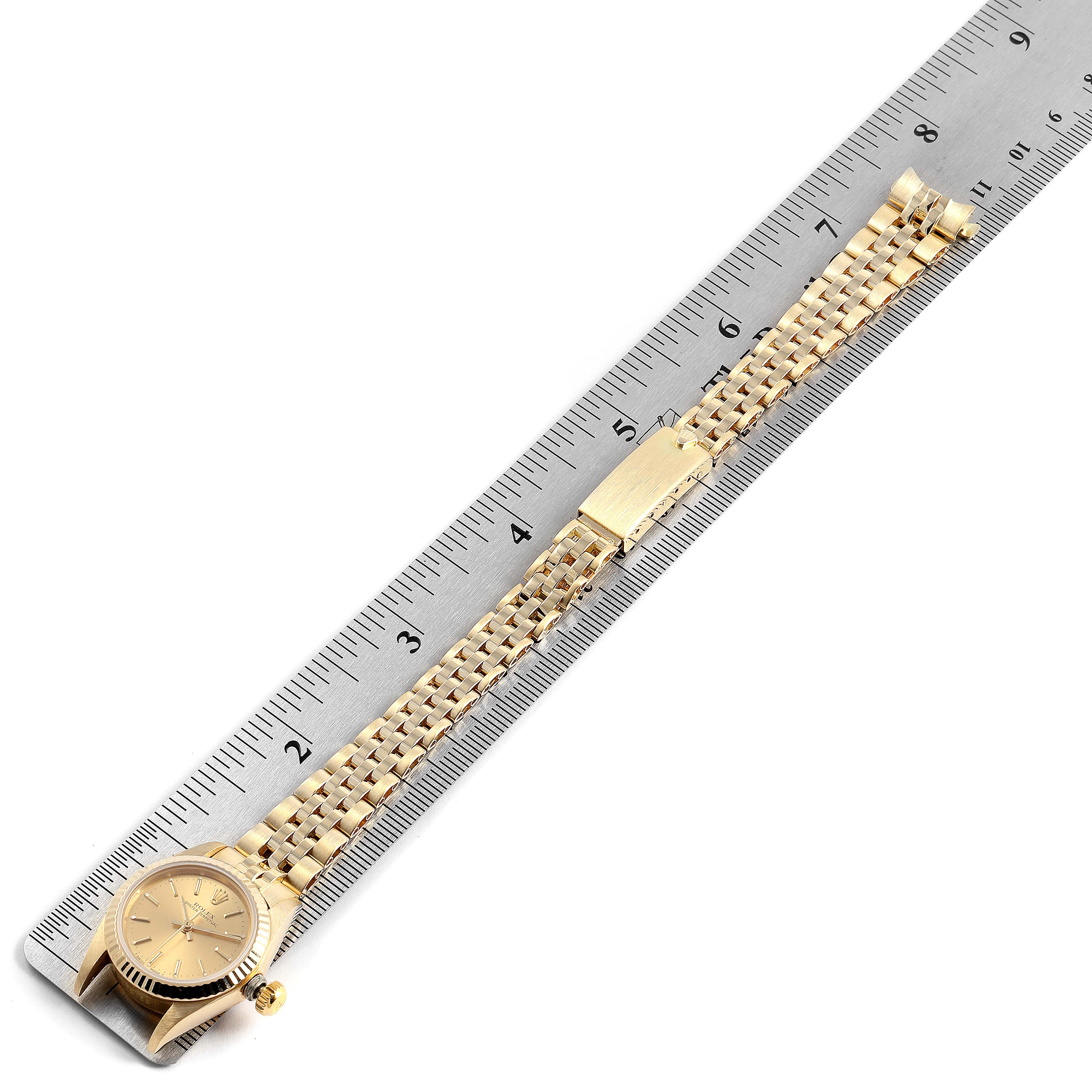 The Rolex President 67198 Women's Yellow Gold Champagne Dial 67198 Women's Yellow Gold Champagne Dial model watch is shown flat, alongside a ruler highlighting its band and face.