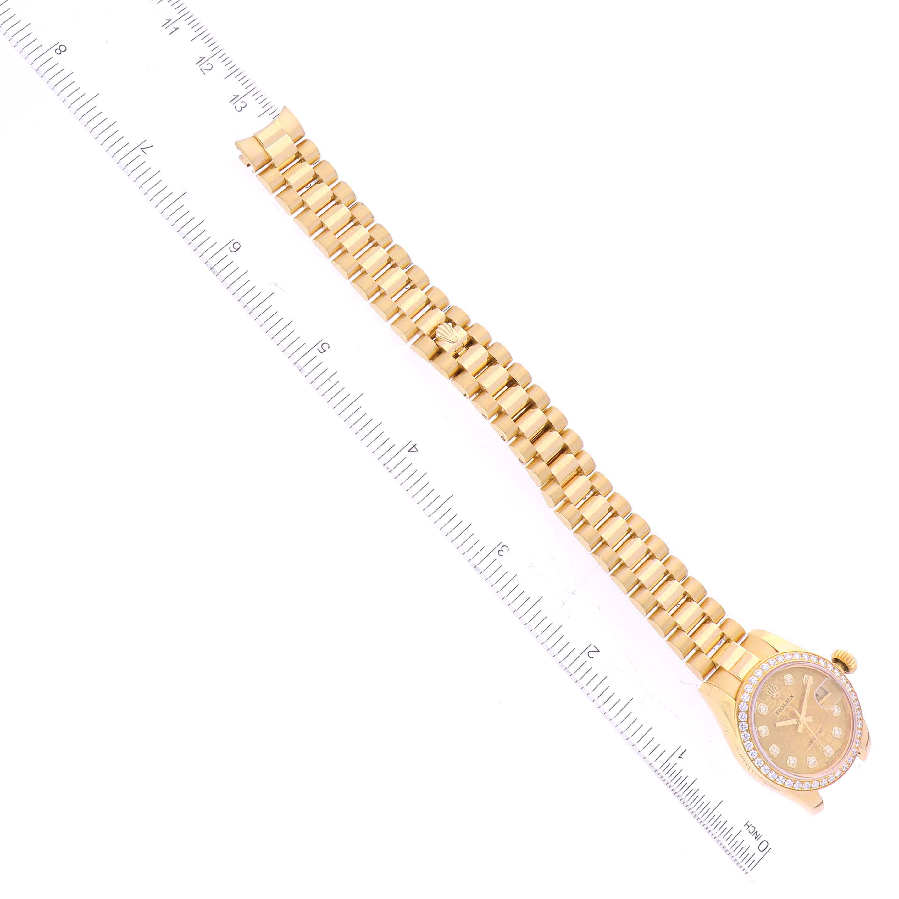 A Rolex President 179138 Women's Yellow Gold Champagne Dial 179138 Women's Yellow Gold Champagne Dial watch is shown lying flat with its face, crown, and bracelet visible alongside a ruler for scale.