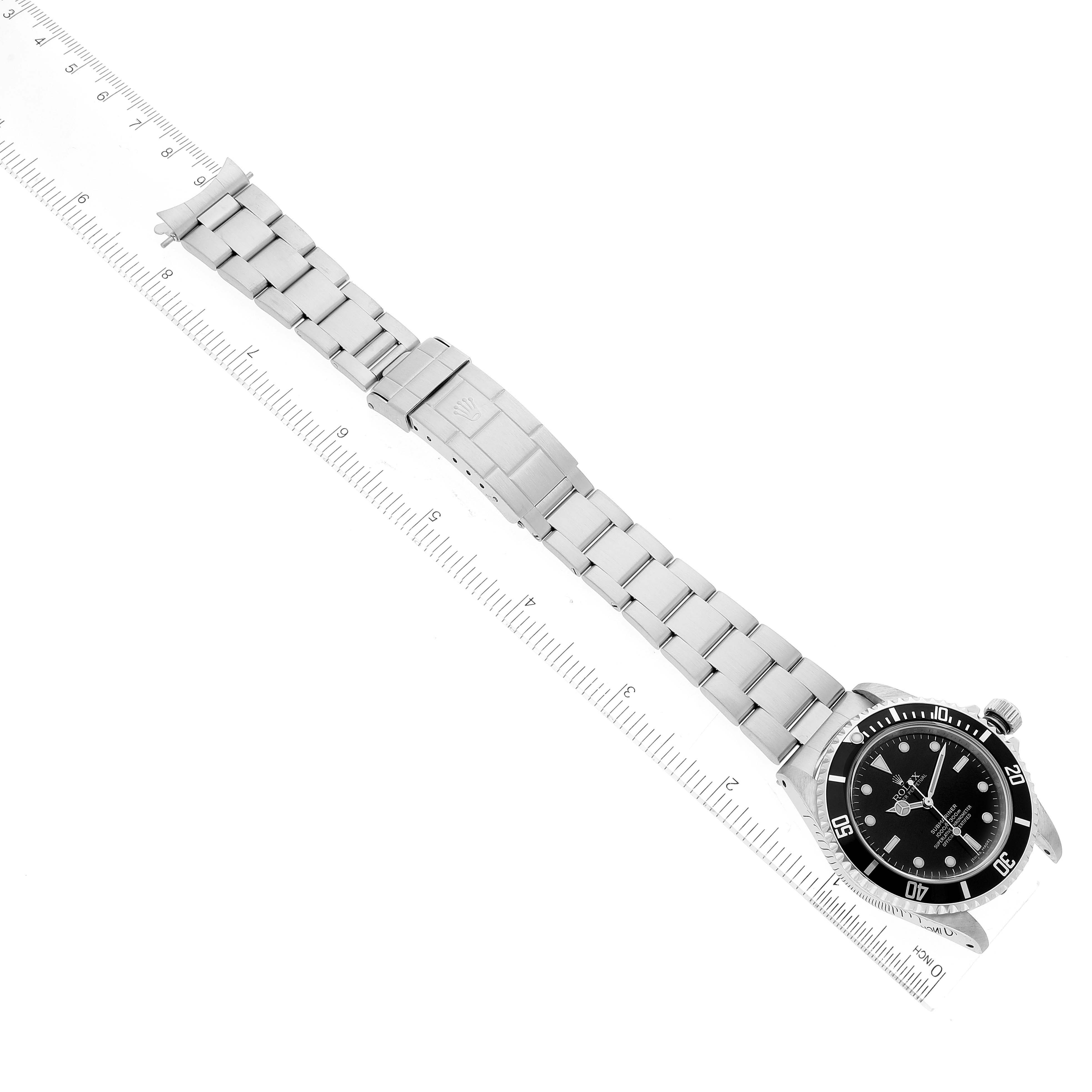 The image shows an overhead view of a Rolex Submariner 14060M Men
s Stainless Steel Black Dial 14060M Men
s Stainless Steel Black Dial watch, including the face, bezel, and full bracelet alongside a ruler.