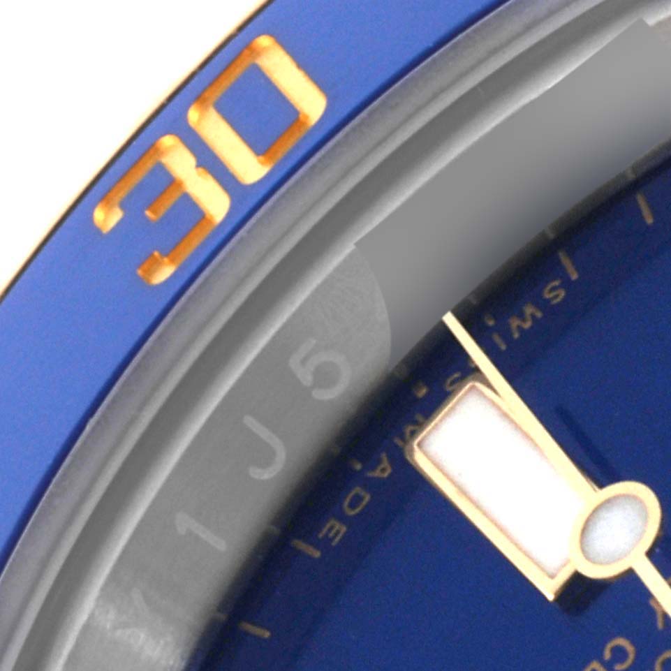 This close-up image of the Rolex Submariner 116613 Men's Steel and Gold (two tone) Blue Dial 116613 Men's Steel and Gold (two tone) Blue Dial watch shows part of the bezel and dial, featuring the "30" minute marker.
