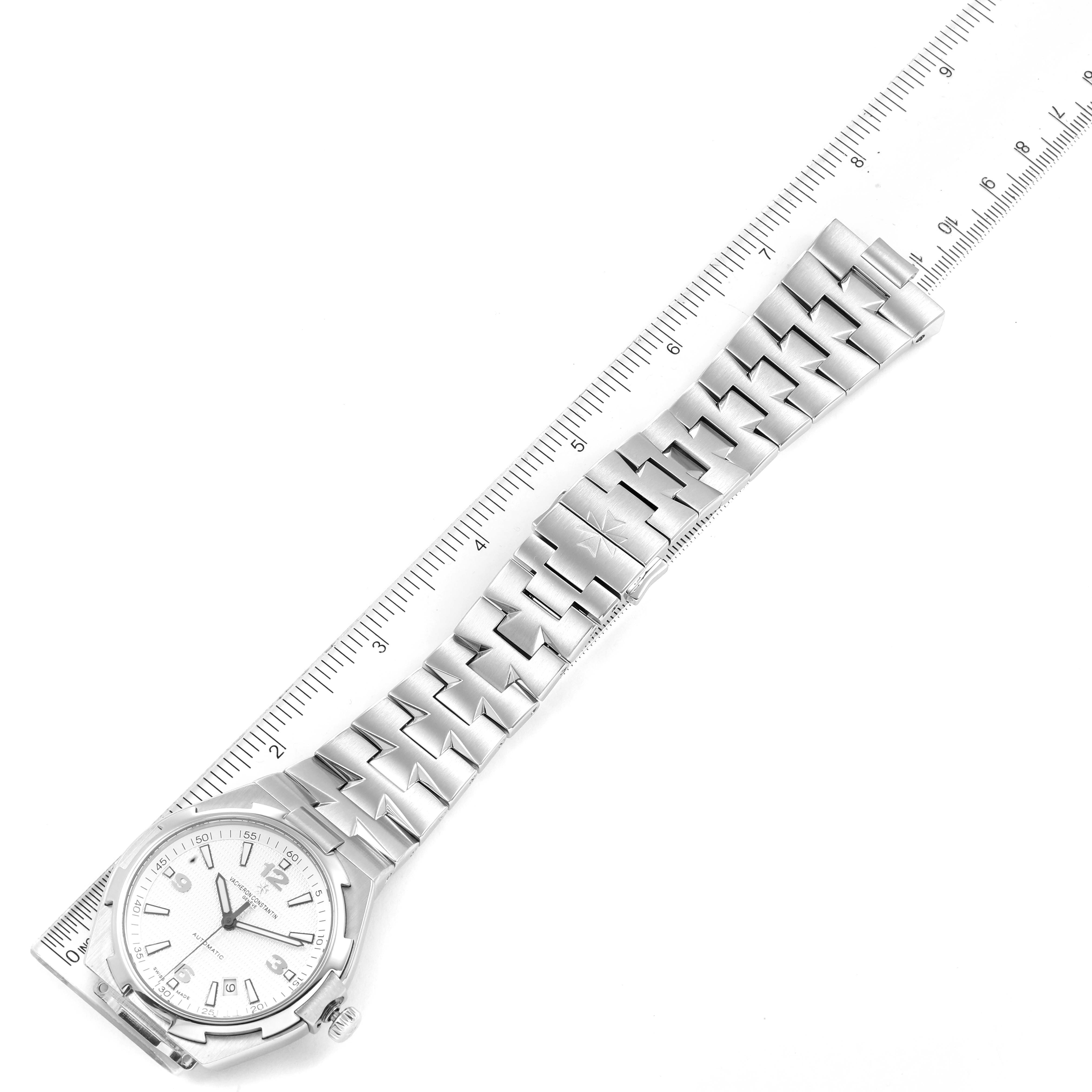 The image shows a Vacheron Constantin Overseas 47040B01A-9093 Men's Stainless Steel Silver Dial 47040B01A-9093 Men's Stainless Steel Silver Dial watch with a metal bracelet, aligned beside a ruler for measurement.