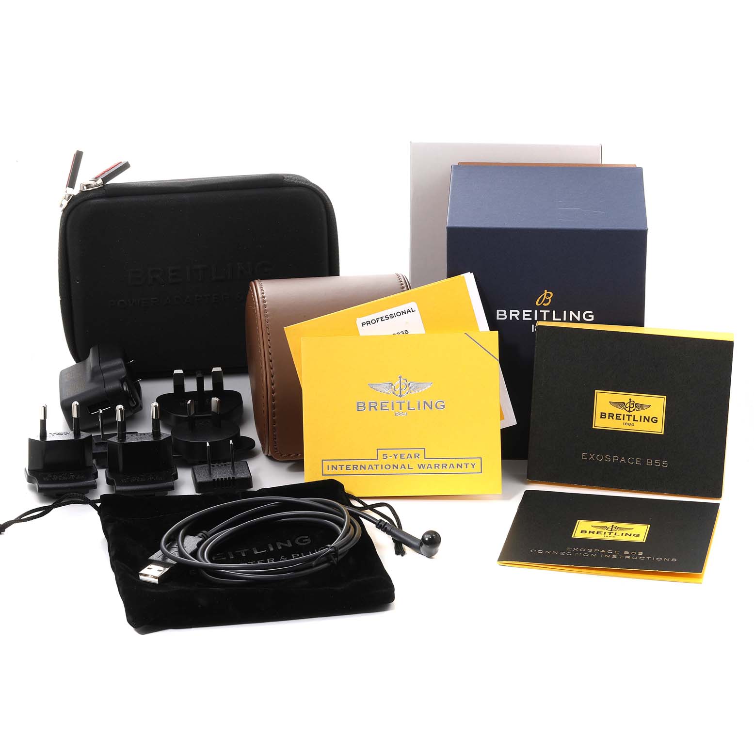 The image shows accessories for the Professional Series model by Breitling, including cases, cables, adapters, and documents.