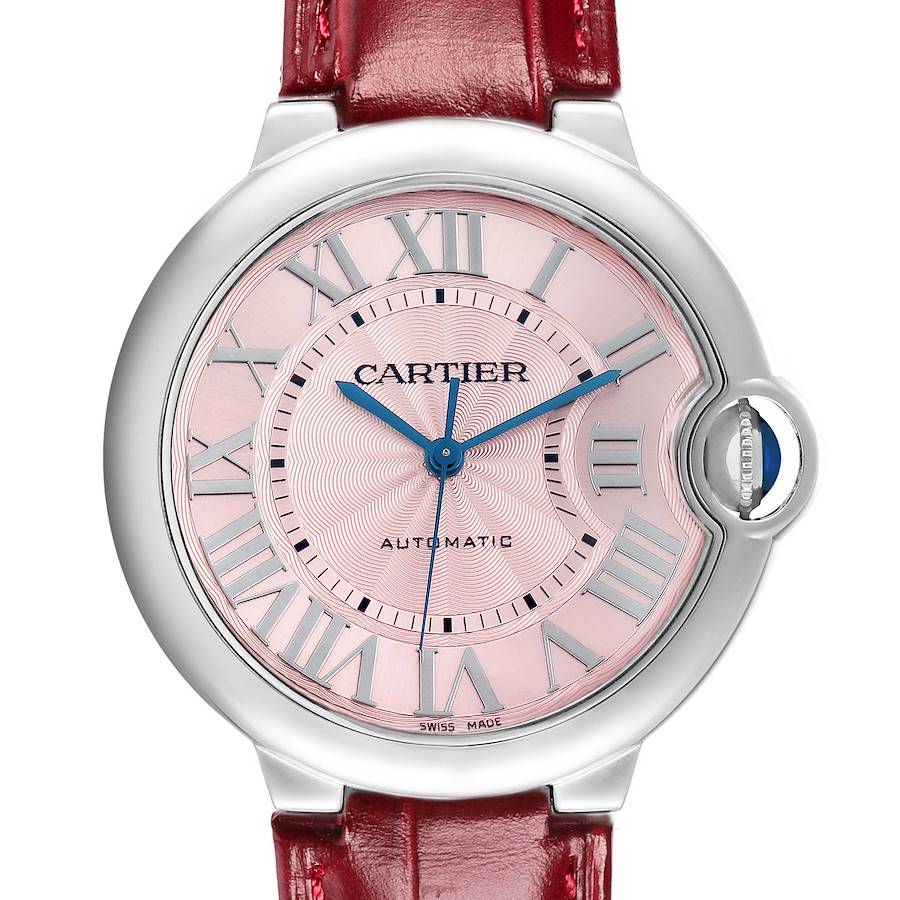 The Ballon Bleu by Cartier is shown from the front, displaying the pink dial, blue hands, Roman numerals, and a red strap.