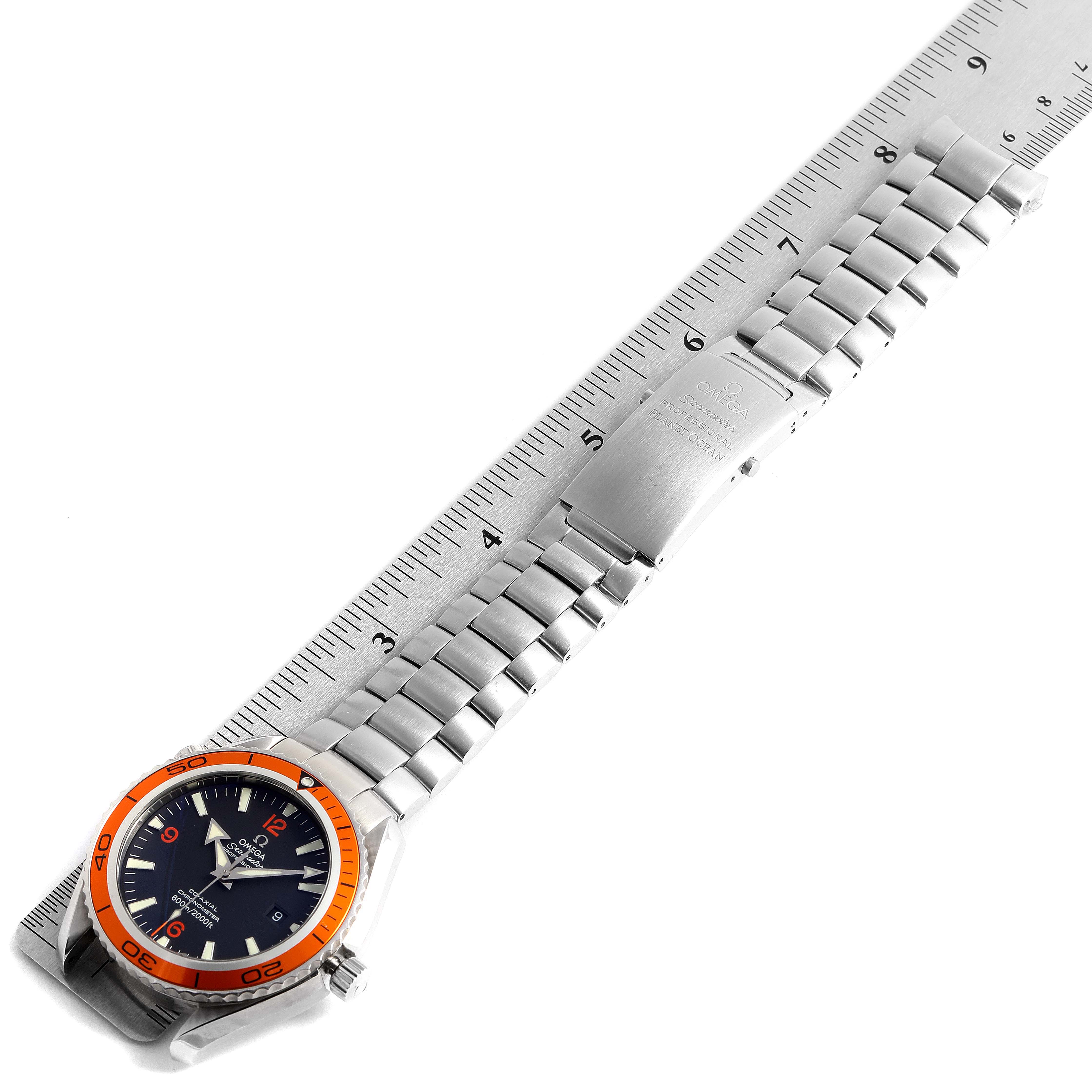 The Omega Planet Ocean 232.30.46.21.01.002 Men's Stainless Steel Black Dial 232.30.46.21.01.002 Men's Stainless Steel Black Dial watch is shown laid flat alongside a ruler, displaying its face, bezel, and metal bracelet.