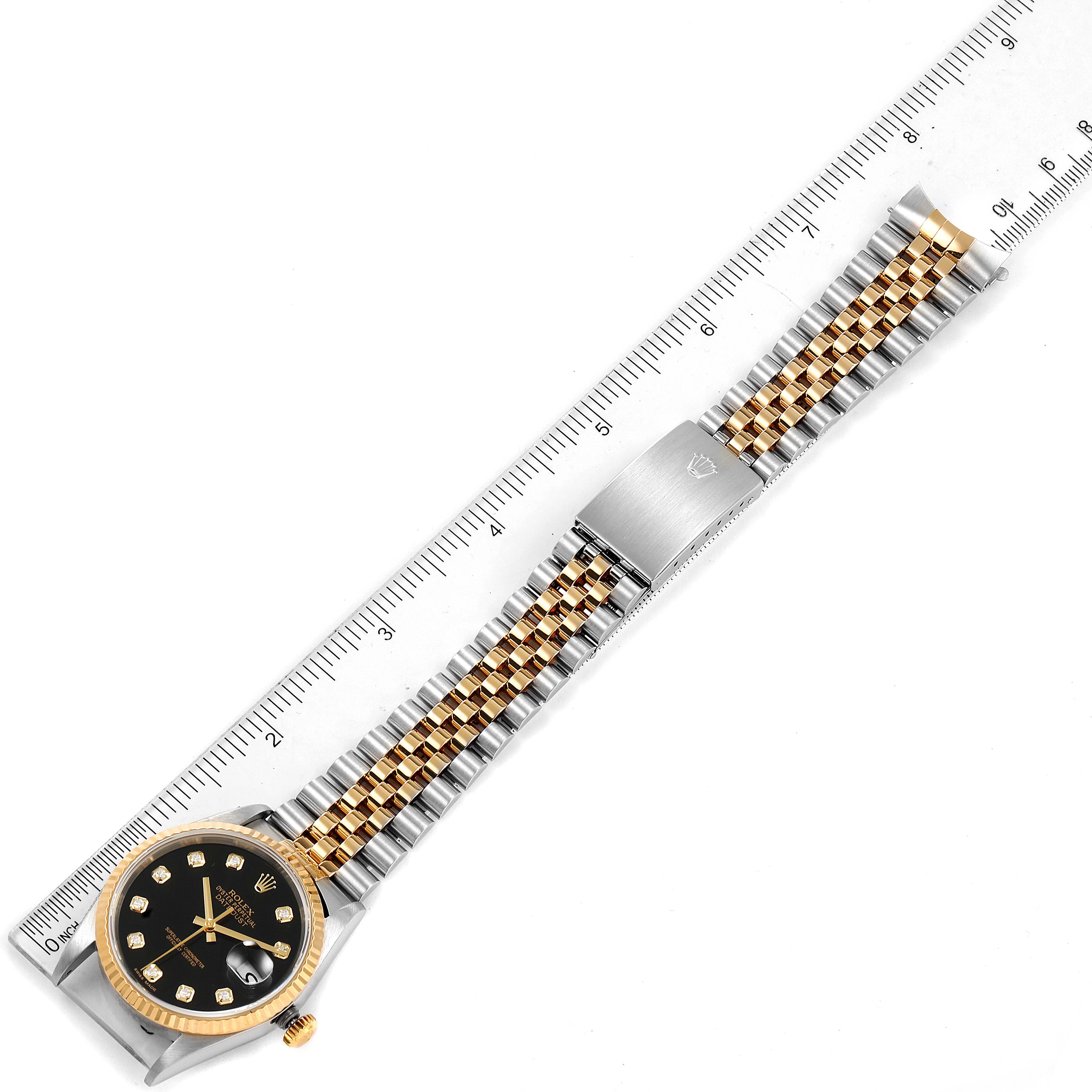 This is a top-down view of a Rolex Datejust 16233 Men's Steel and Gold (two tone) Black Dial 16233 Men's Steel and Gold (two tone) Black Dial, showing the watch face, bracelet, and clasp, alongside a measuring ruler.
