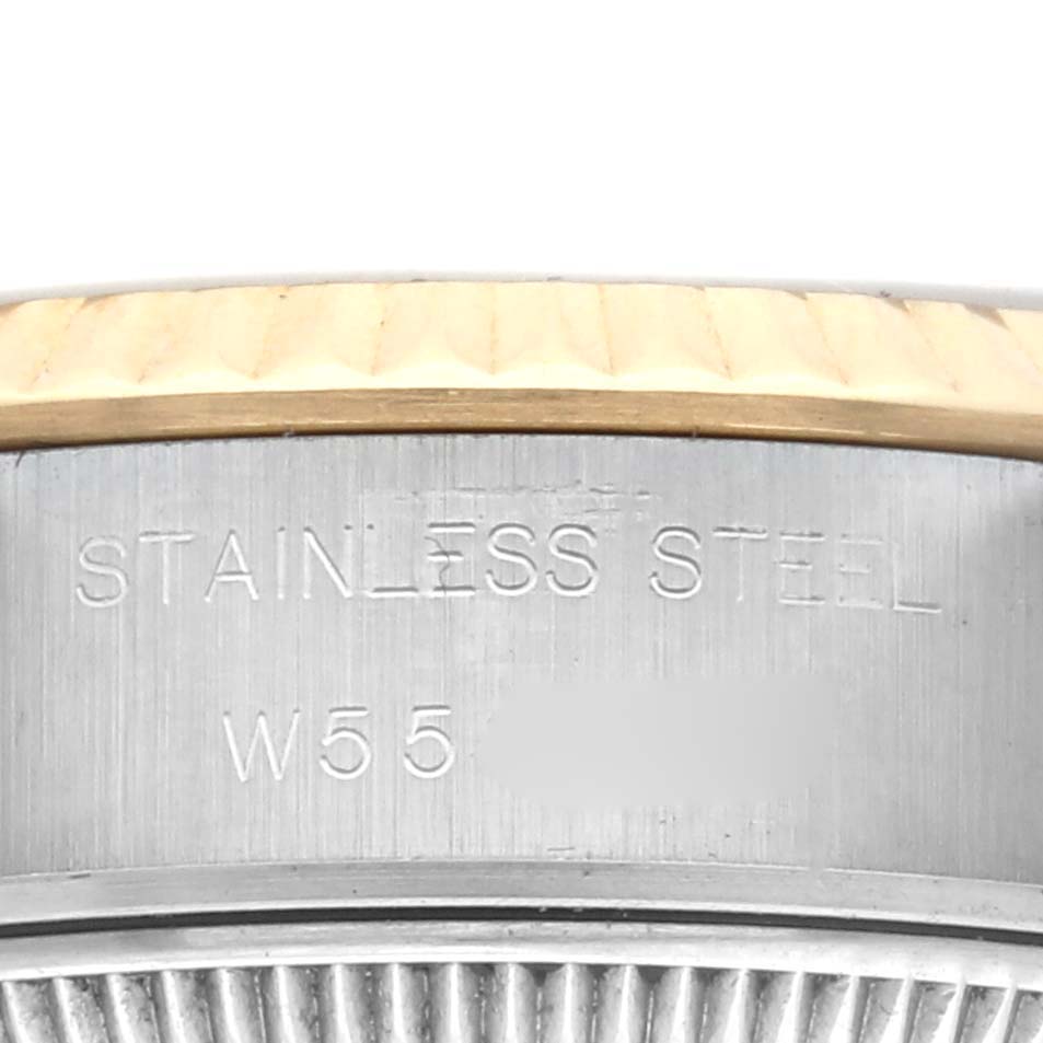 The image shows a close-up of a Rolex Datejust 69173 Women
s Steel and Gold (two tone) Champagne Dial
s fluted bezel and case with "STAINLESS STEEL" engraved on the side.
